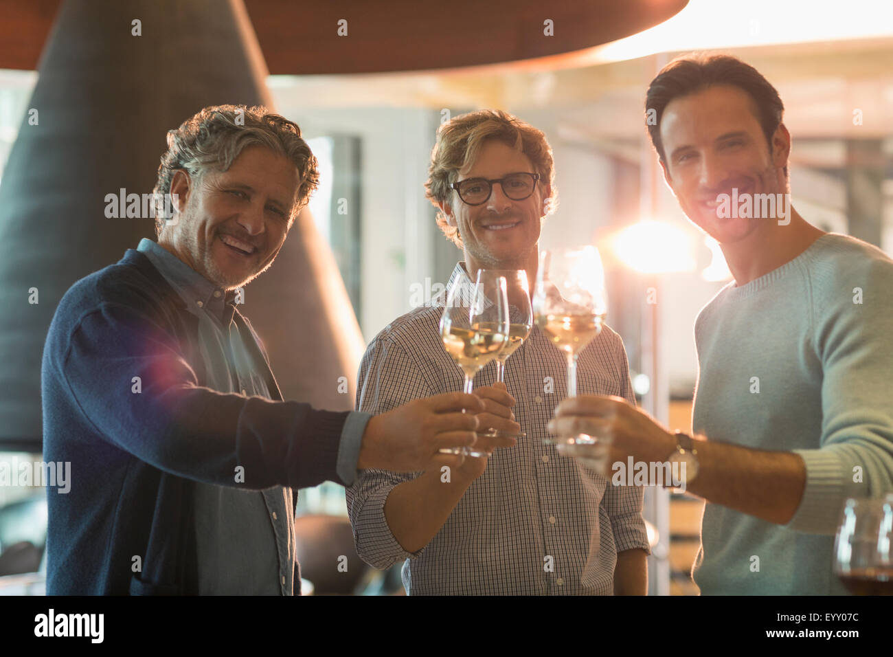 Retrato sonriente hombres bebiendo vino blanco en la bodega Foto de stock