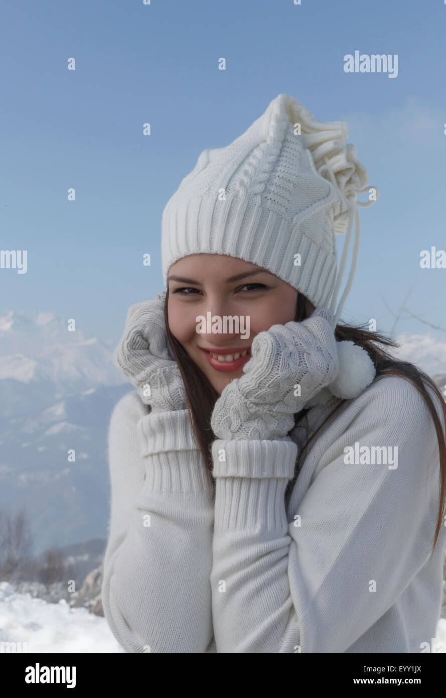 Mujer con ropa de abrigo poniéndose guantes en invierno con nieve