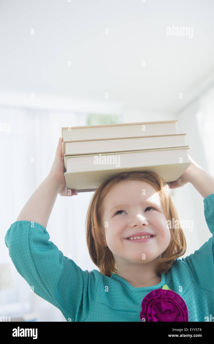 Chica caucásica equilibrando los libros en la cabeza. Foto de stock