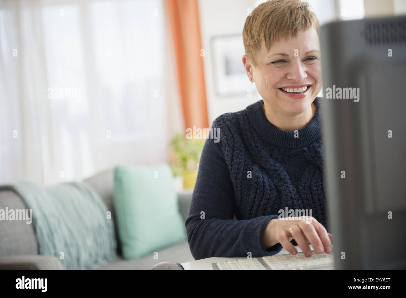 Laughing mujer caucásica utilizando el ordenador Foto de stock