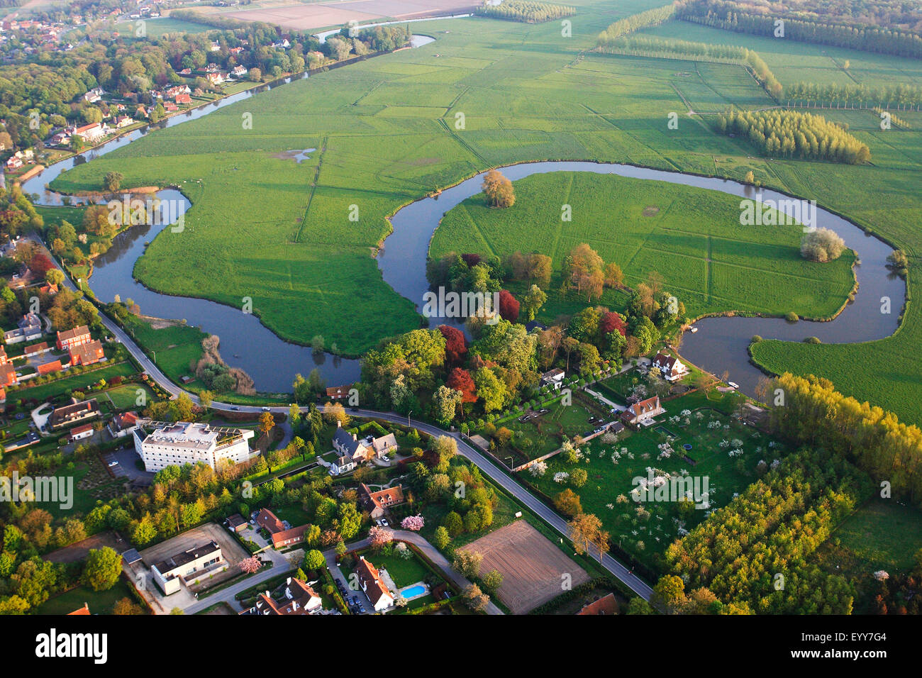 Vista aérea al borde de una aldea y prados junto al antiguo meandro del río Leie, Bélgica, Leie Foto de stock