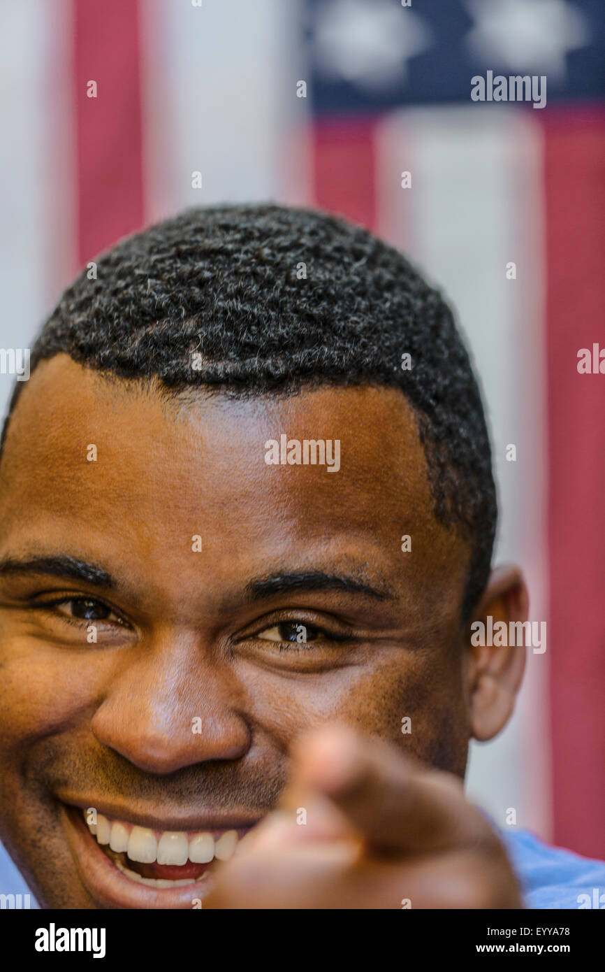 Primer plano de un hombre negro sonriente hacia delante de la bandera americana Foto de stock
