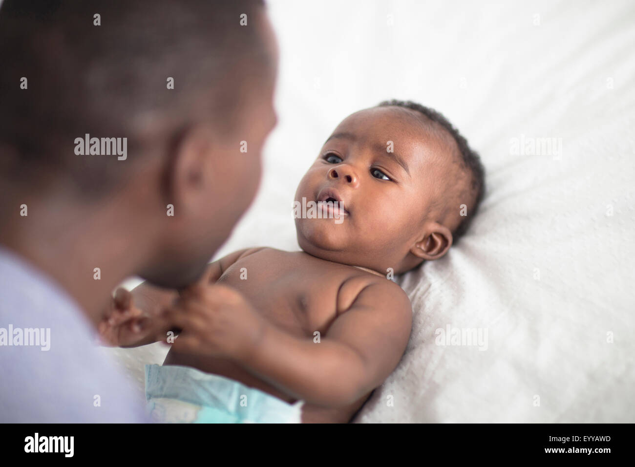 Cerca de padre Negro jugando con el bebé en la cama Foto de stock