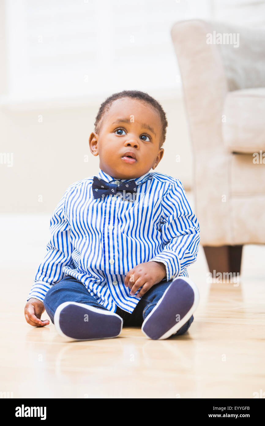 Baby Boy negro sentado en el suelo del cuarto de estar Foto de stock