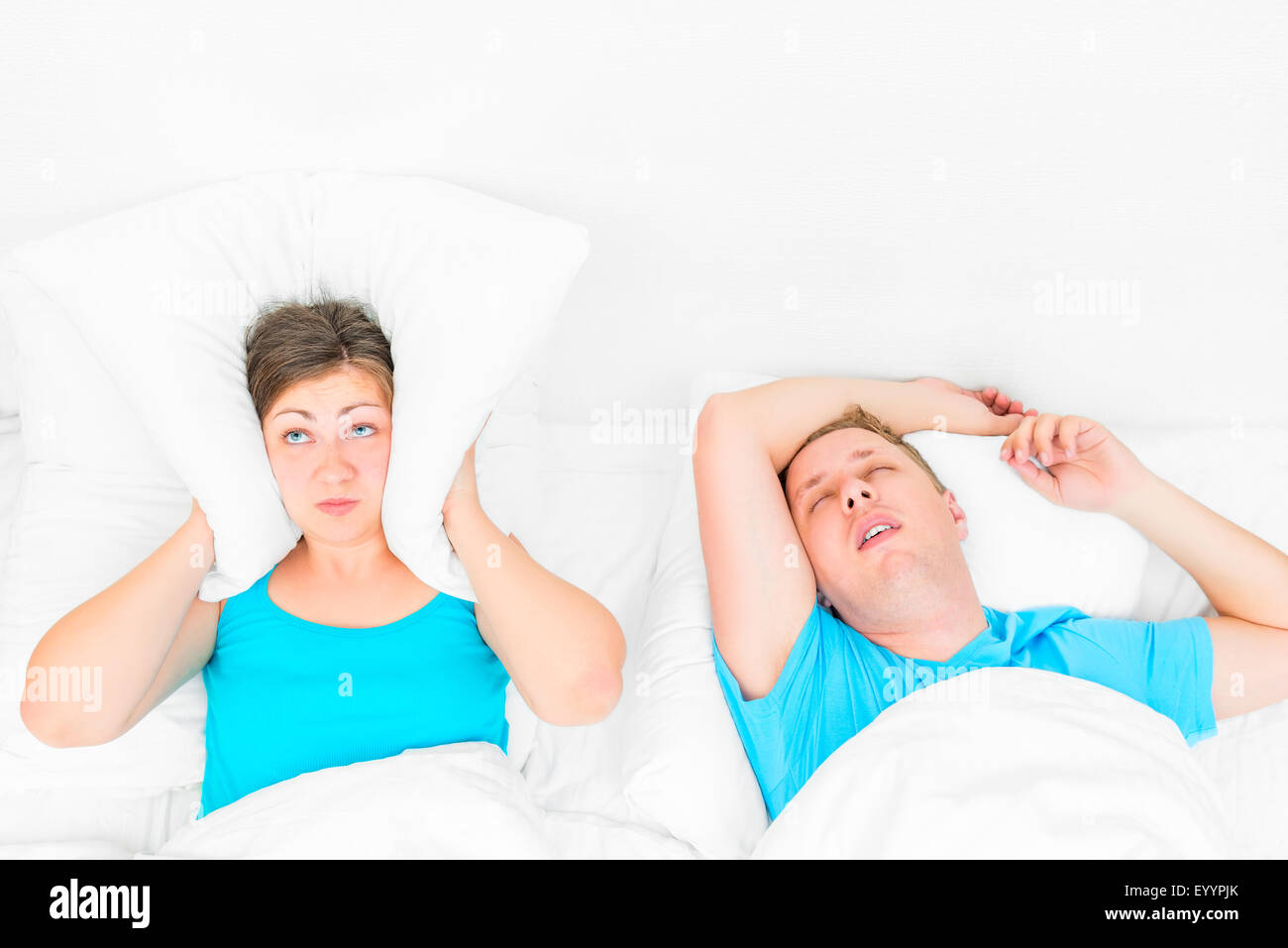 La mujer no puede dormir de ronquidos marido, la almohada cubriendo sus orejas Foto de stock