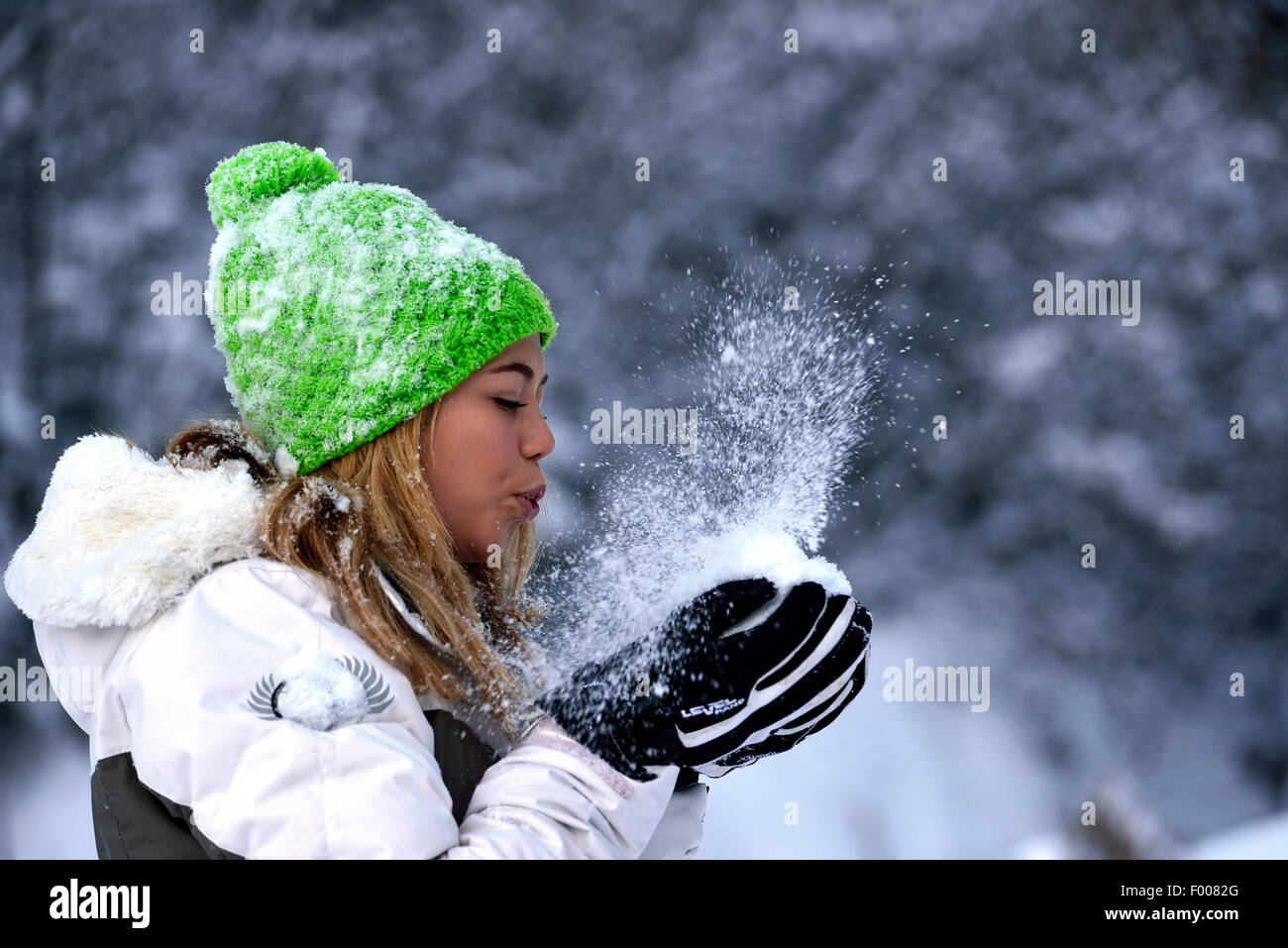 Alegre guapo joven soplando en la nieve en sus manos, Francia, Savoie Foto de stock