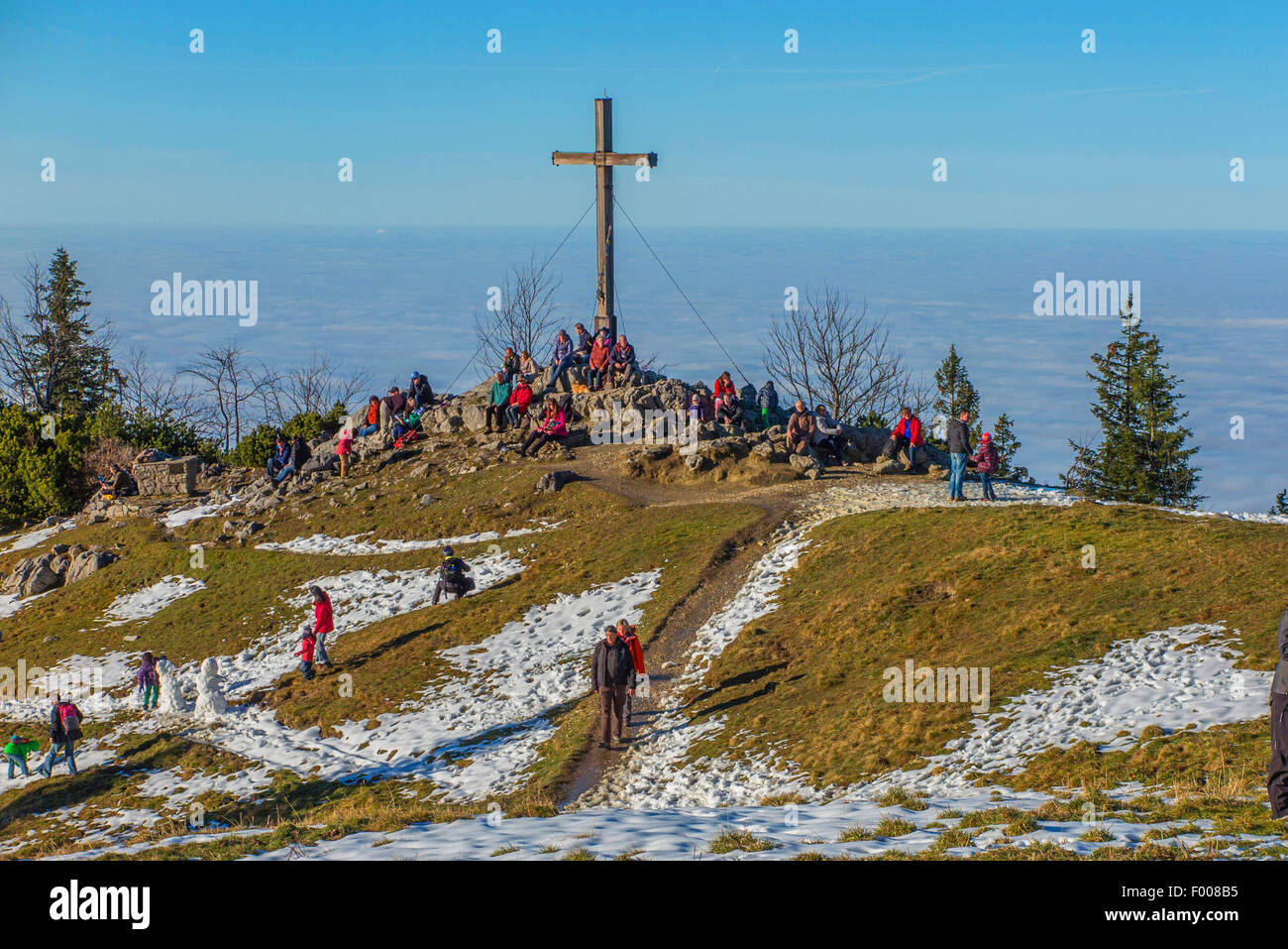 Cruz en la cima de la montaña de sol y niebla en el valle, Alemania, Baviera, Kampenwand, Hohenaschau Foto de stock