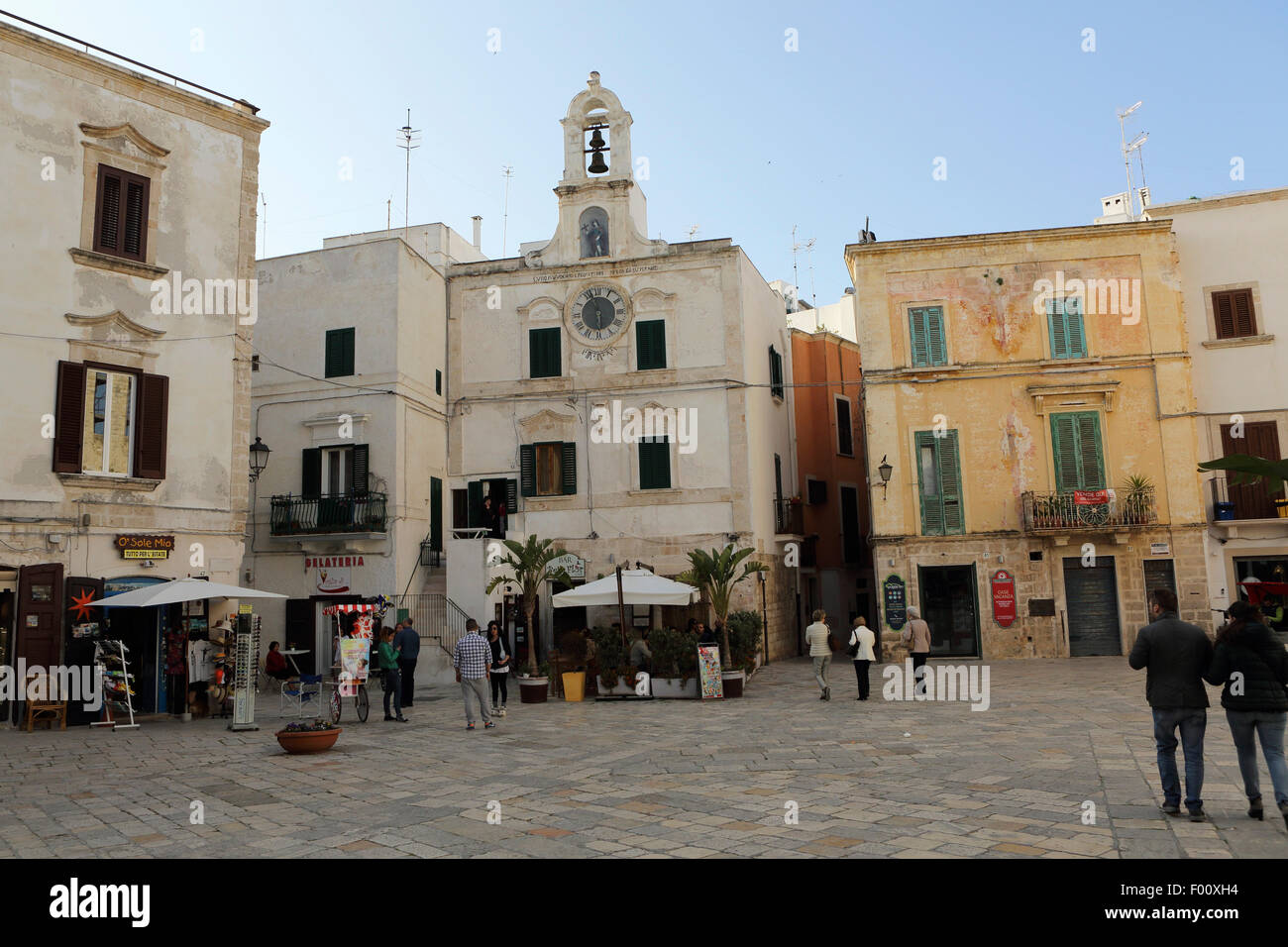 Tiendas, cafés y el campanario de una iglesia matriarcal (Chiesa Matrice) en Polignano a Mare en Apulia, Italia. Foto de stock
