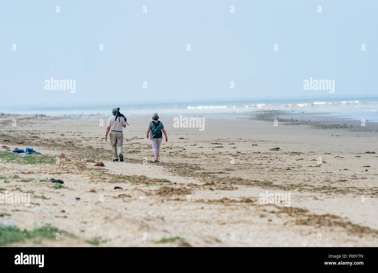 Macho y hembra ancianos observadores de aves caminando por la costa en Titchwell, Norfolk, Inglaterra Foto de stock