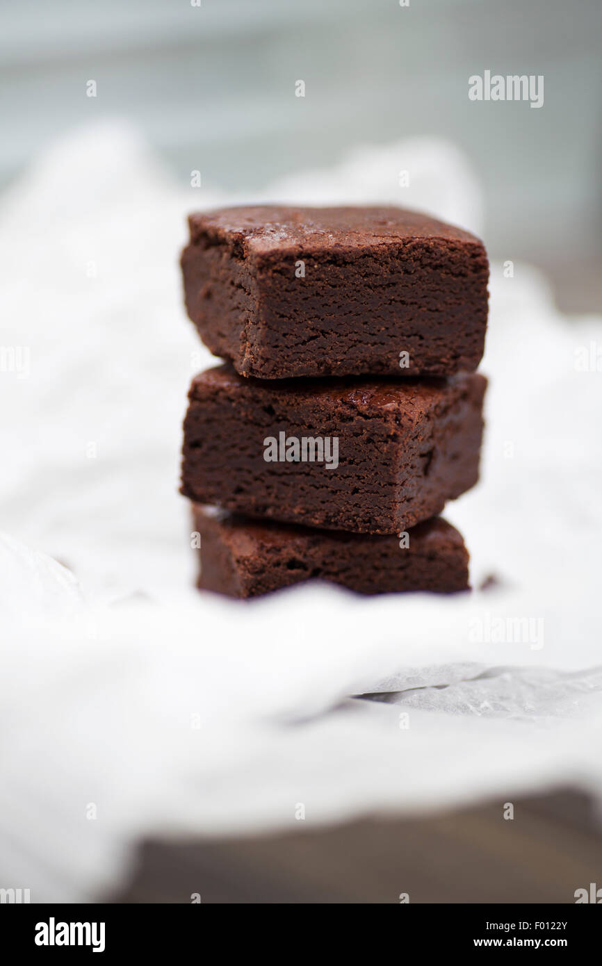 Pila de fresco y chocolate indulgente brownies sobre un fondo de textura Foto de stock