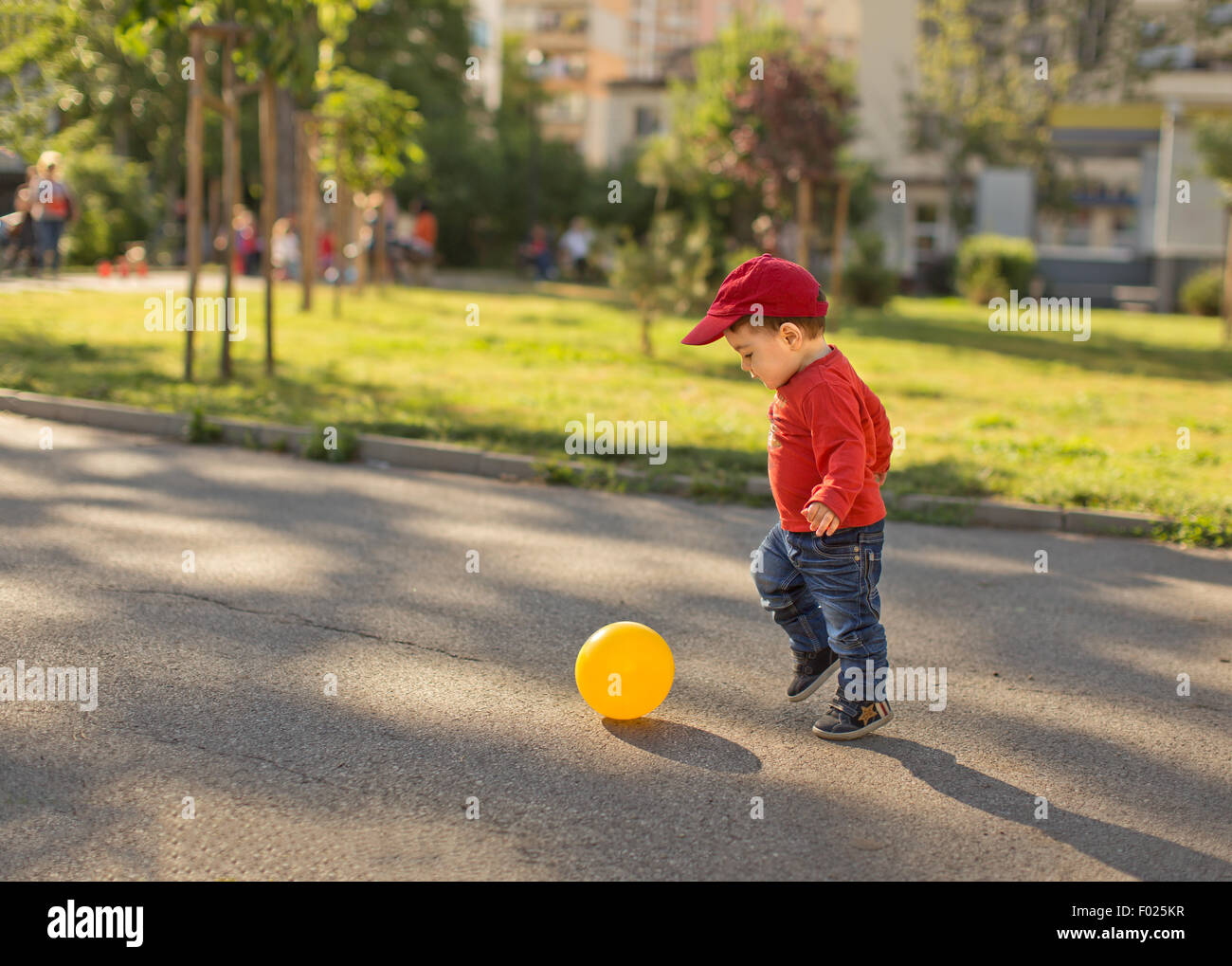 Niño jugando al fútbol en la calle Foto de stock
