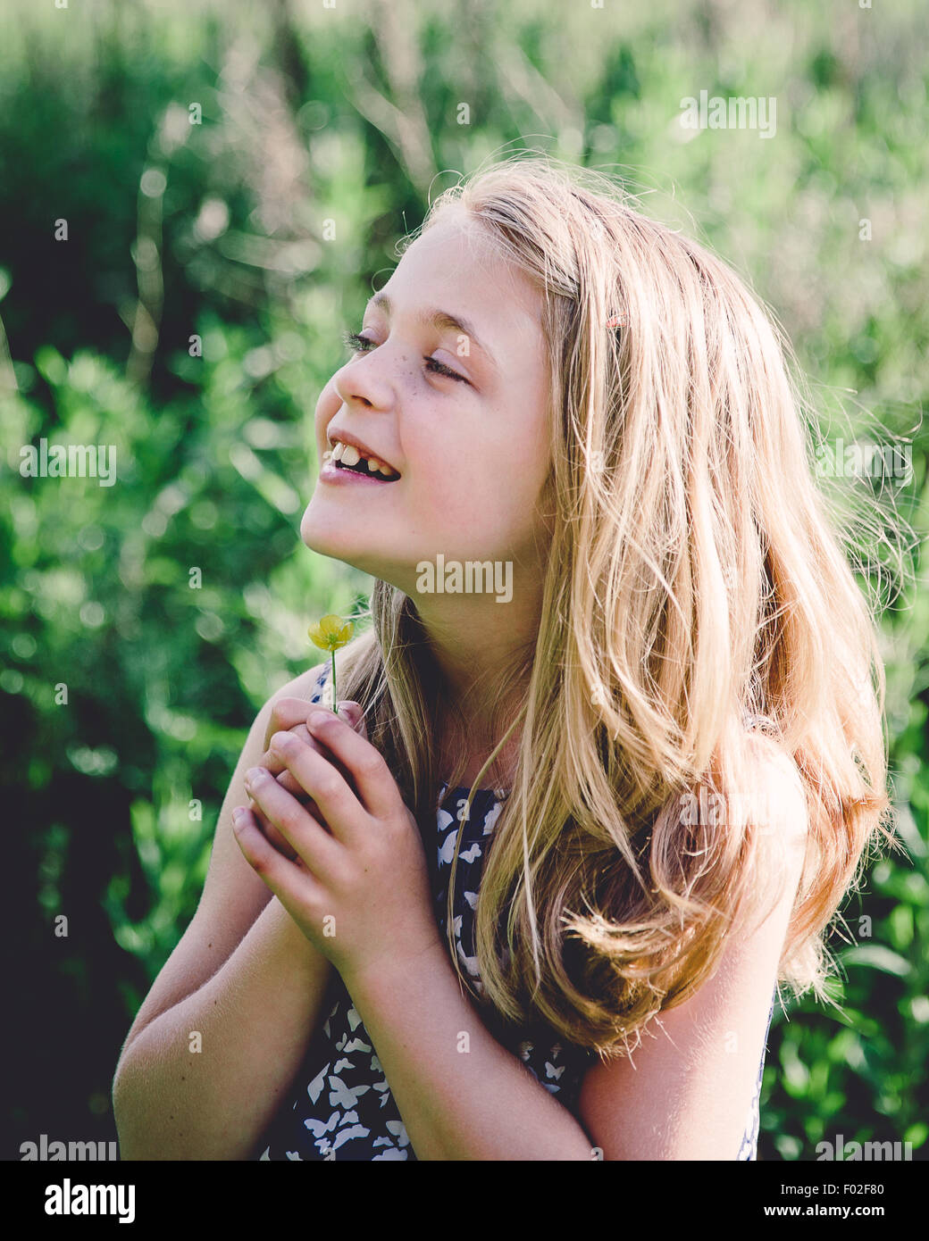 Retrato de una niña sonriente sosteniendo un buttercup bajo su barbilla Foto de stock