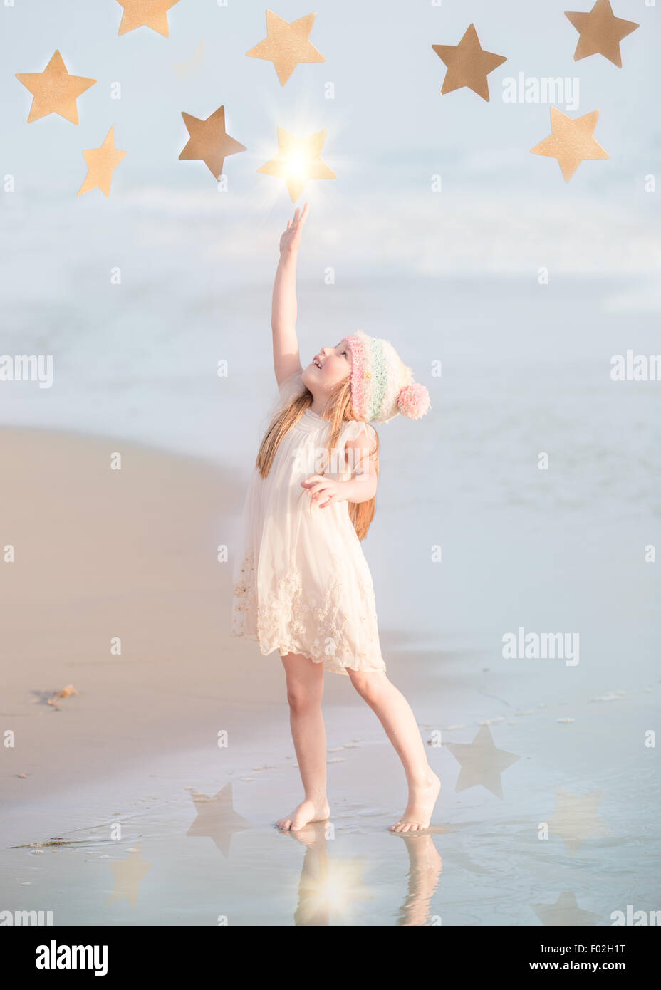 Chica de pie en la playa alcanzando las estrellas, California, Estados Unidos Foto de stock