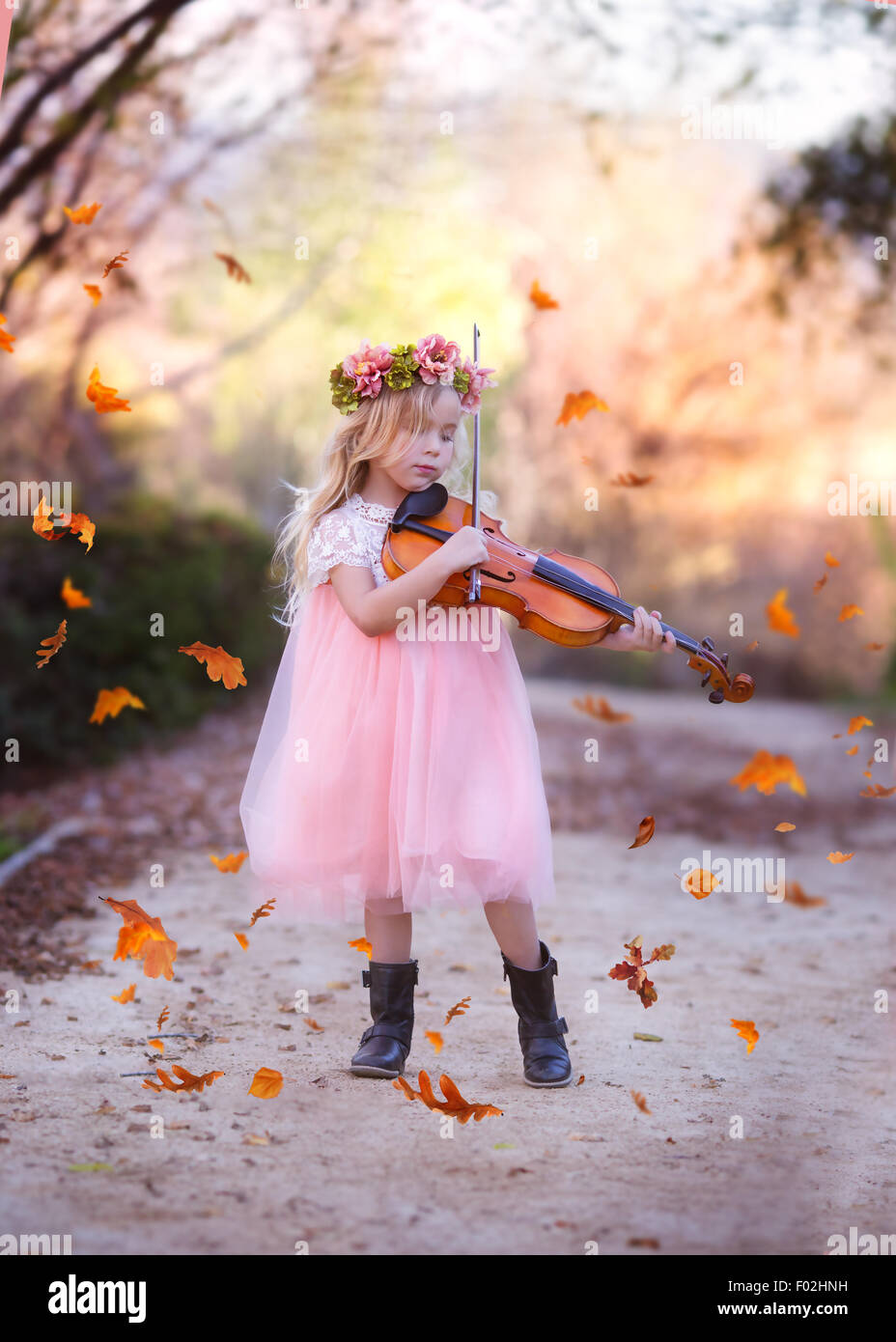 Chica de pie en la carretera tocando el violín con hojas cayendo por todo el mundo, California, EE.UU Foto de stock