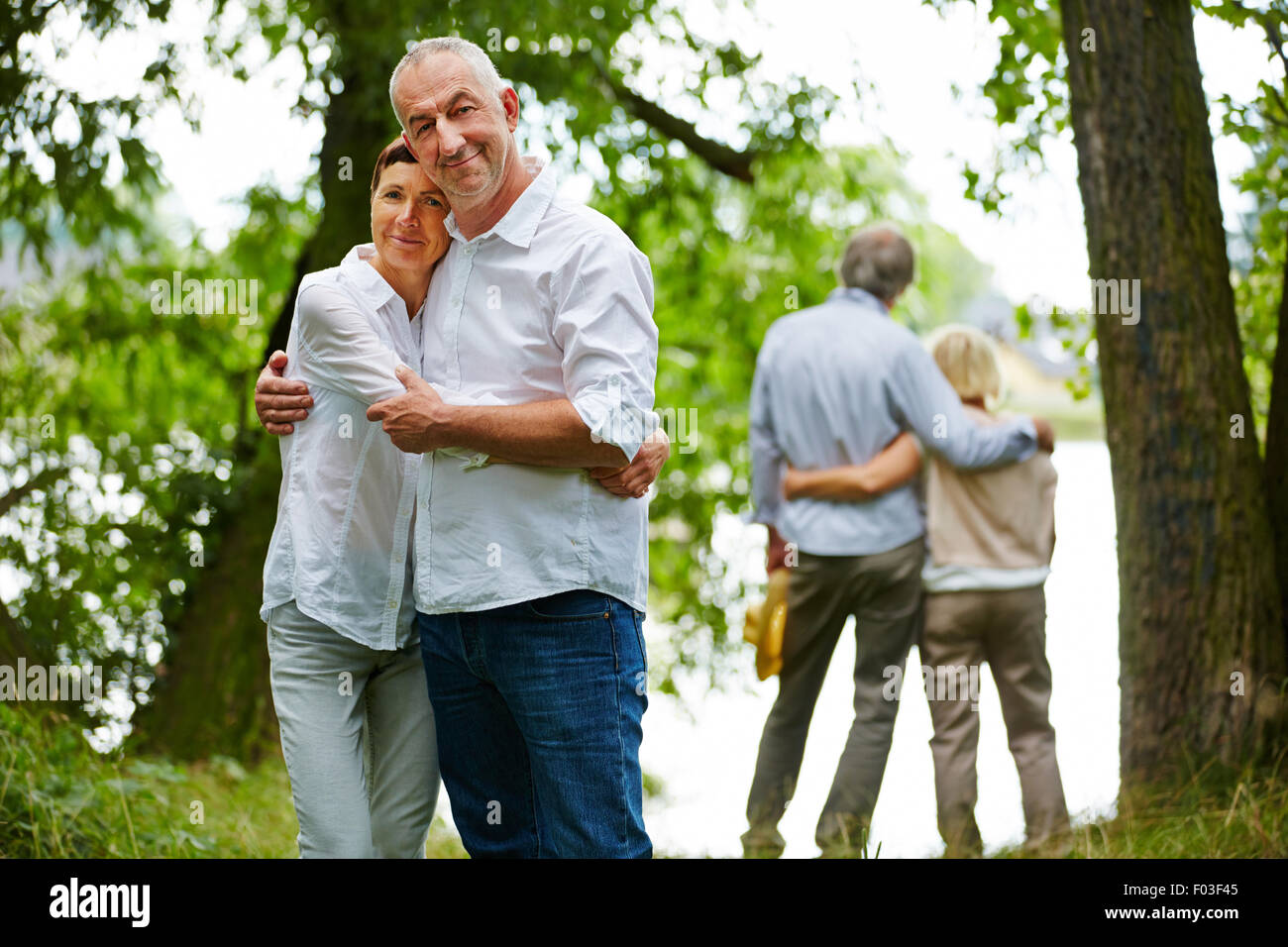 Dos felices parejas senior abrazar en el jardín de la casa de retiro Foto de stock