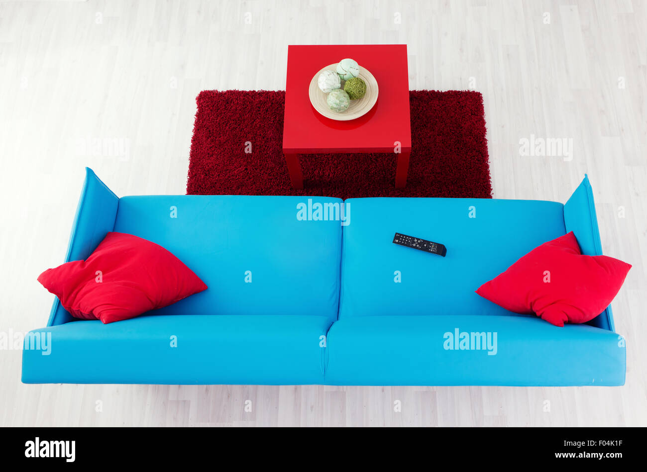 Sofá azul con rojo rojo de almohadas y mesa de café, vista superior Foto de stock
