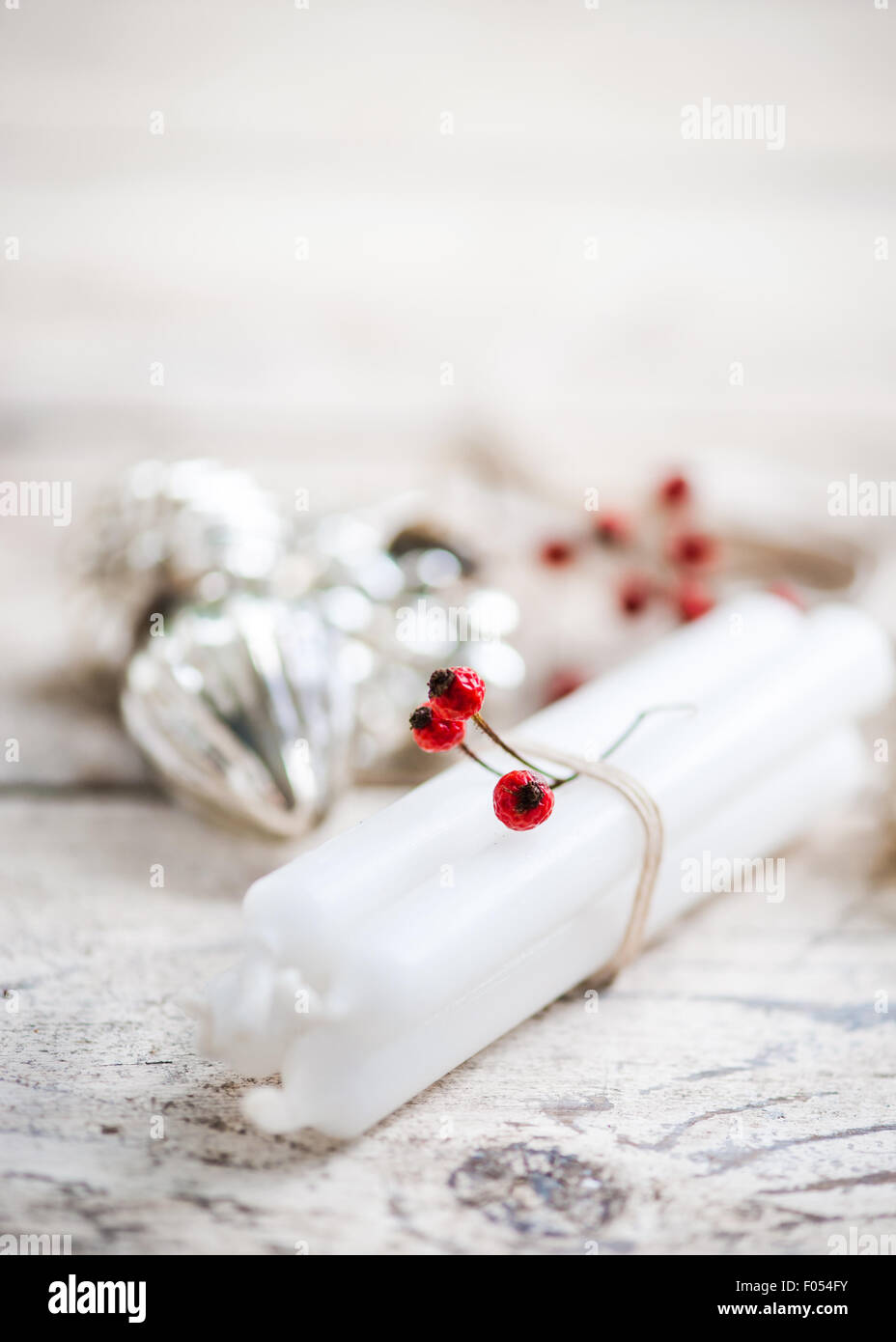 Velas blancas atadas con cordel, bayas rojas y bolas de plata Foto de stock