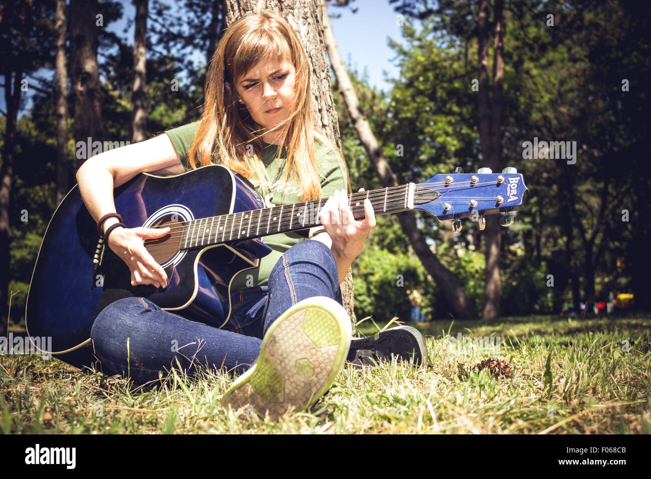 Chica cantando a la guitarra, rodeada de árboles en un parque Fotografía de  stock - Alamy