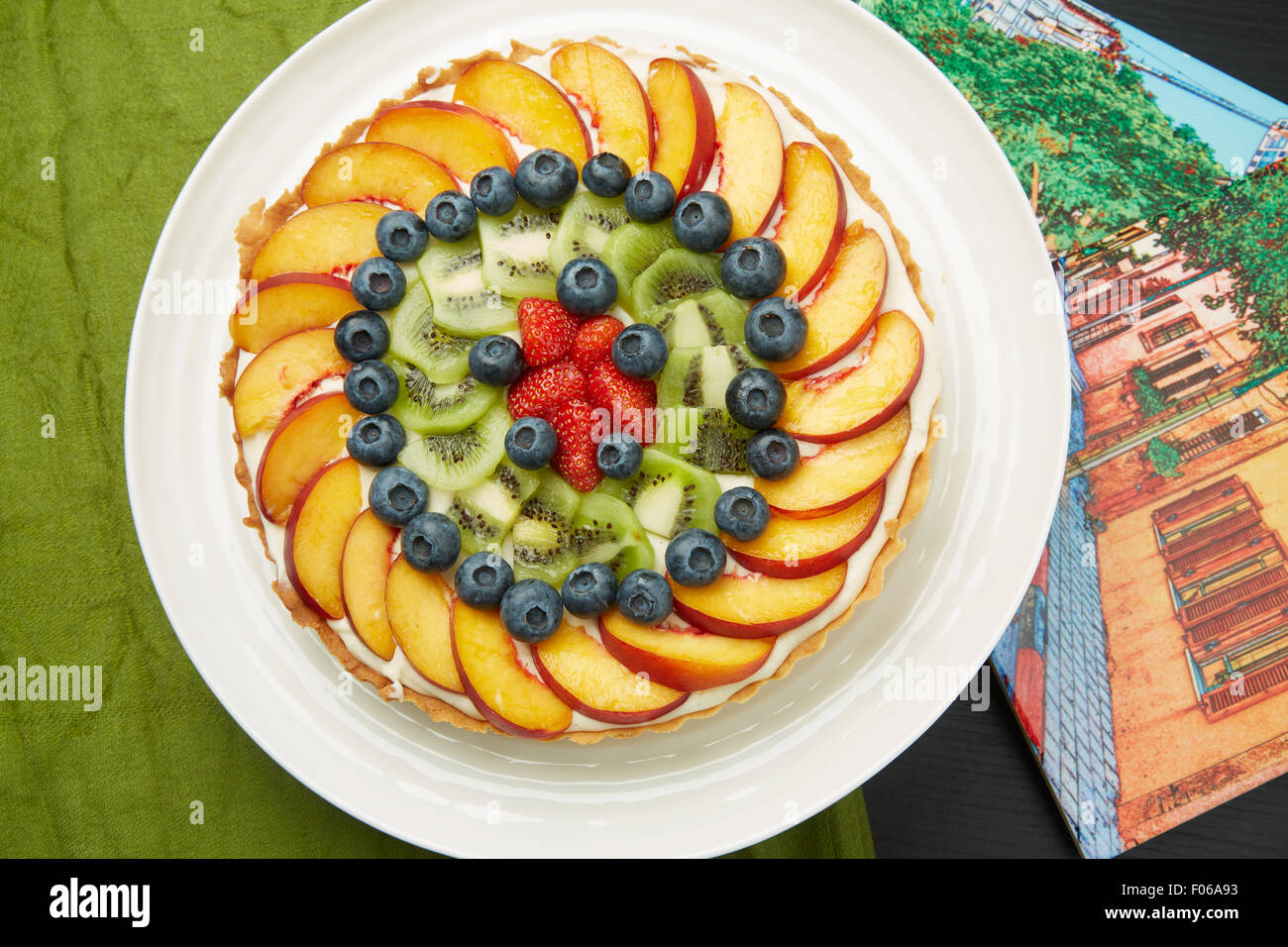 Un alto ángulo de visualización de una deliciosa tarta con Berry, manzanas y kiwis en un plato redondo blanco servido en la mesa. Foto de stock