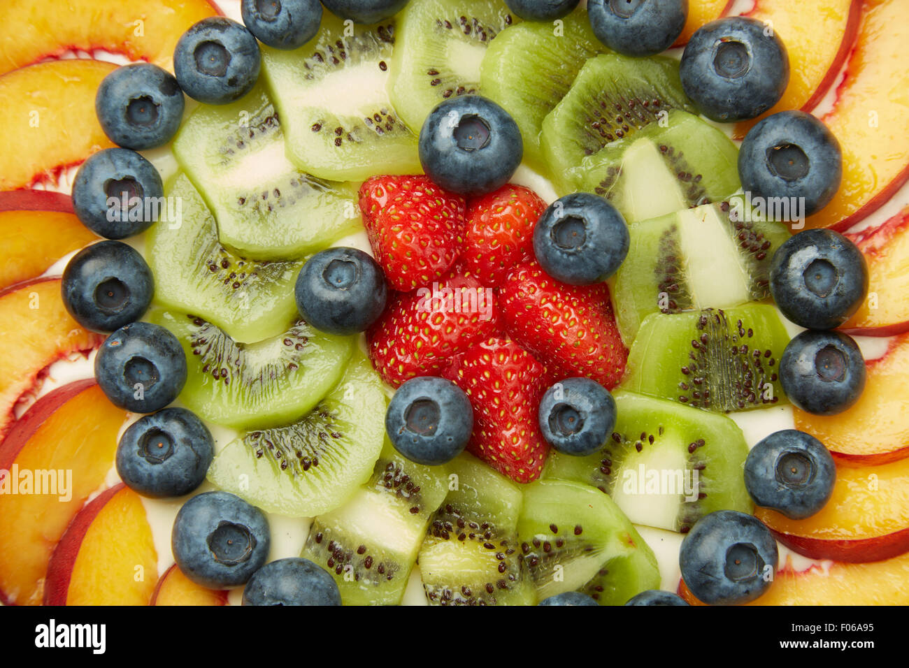 Un alto ángulo de disparo de arándanos frescos, fresas, manzanas y kiwis en la cima de una deliciosa tarta Foto de stock