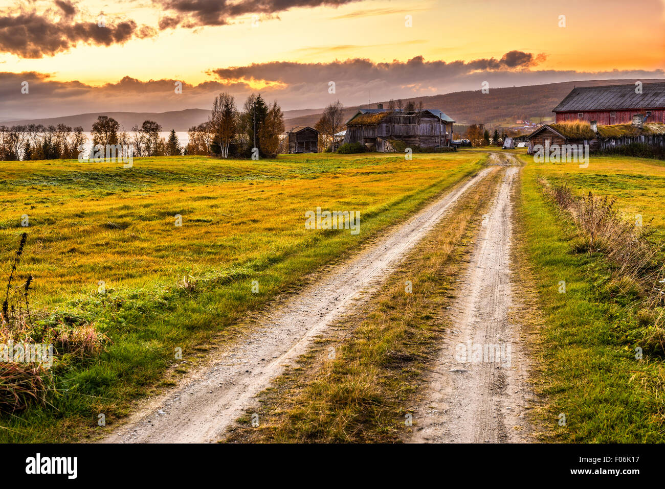 Icónica granero de madera con granja y camino rural al atardecer en Noruega Foto de stock