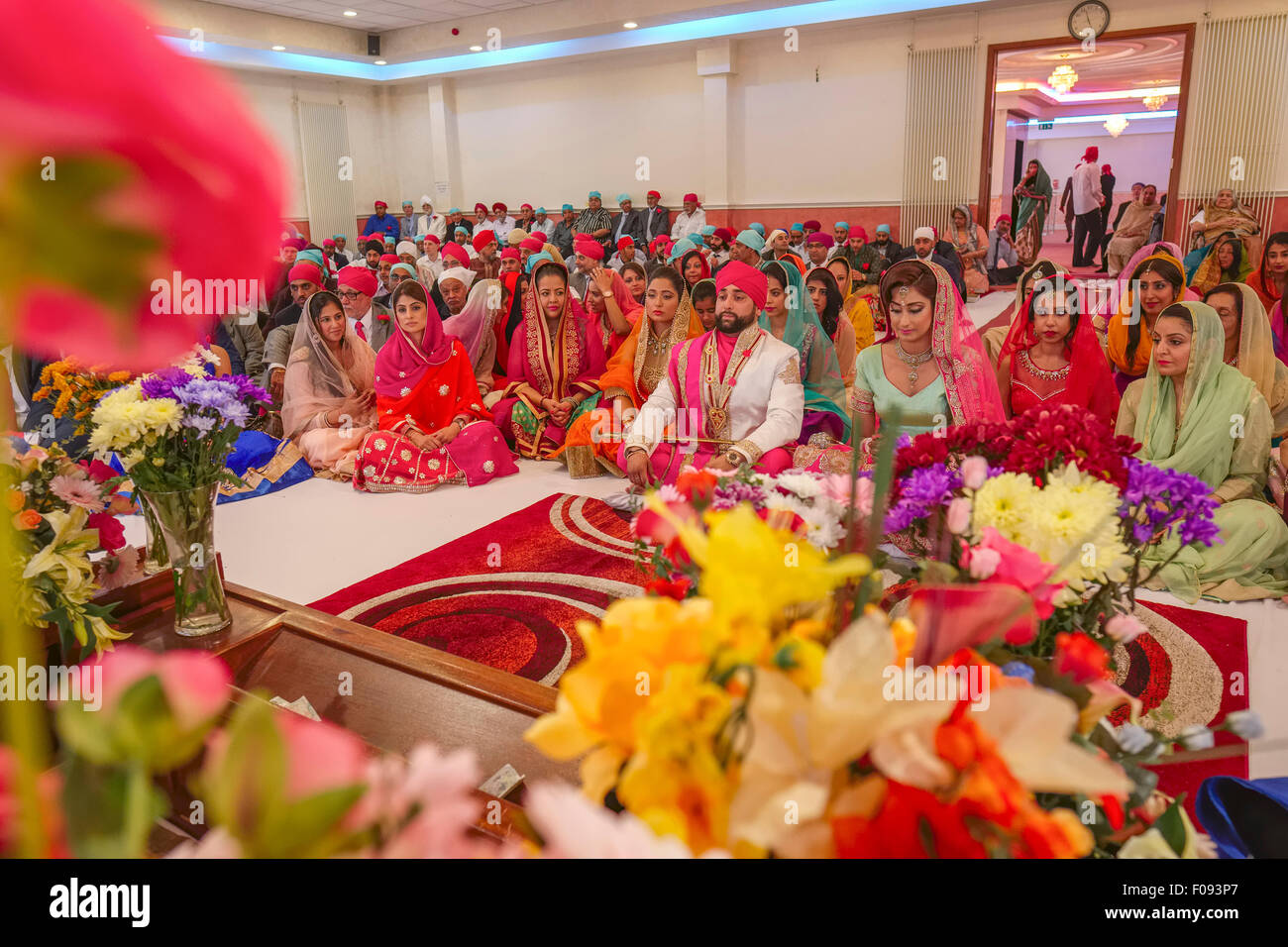 Los invitados a la boda con la novia y el novio en un matrimonio Sikh Gurdwara Brent en Londres Foto de stock