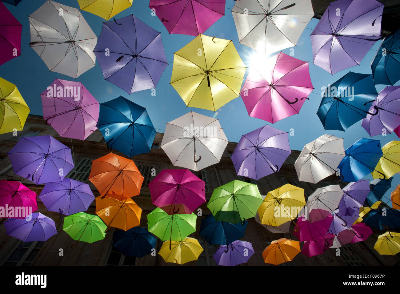 Coloridas sombrillas flotante llenan el cielo sobre la rue Jean Jaures, Arles, Bouches-du-Rhône, departamento de Provence, Francia Foto de stock