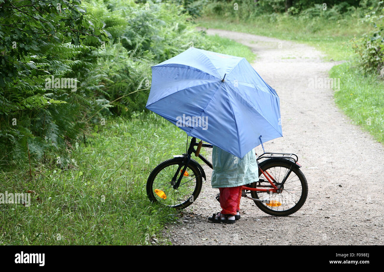 Niño en bicicleta con paraguas azul Fotografía stock - Alamy