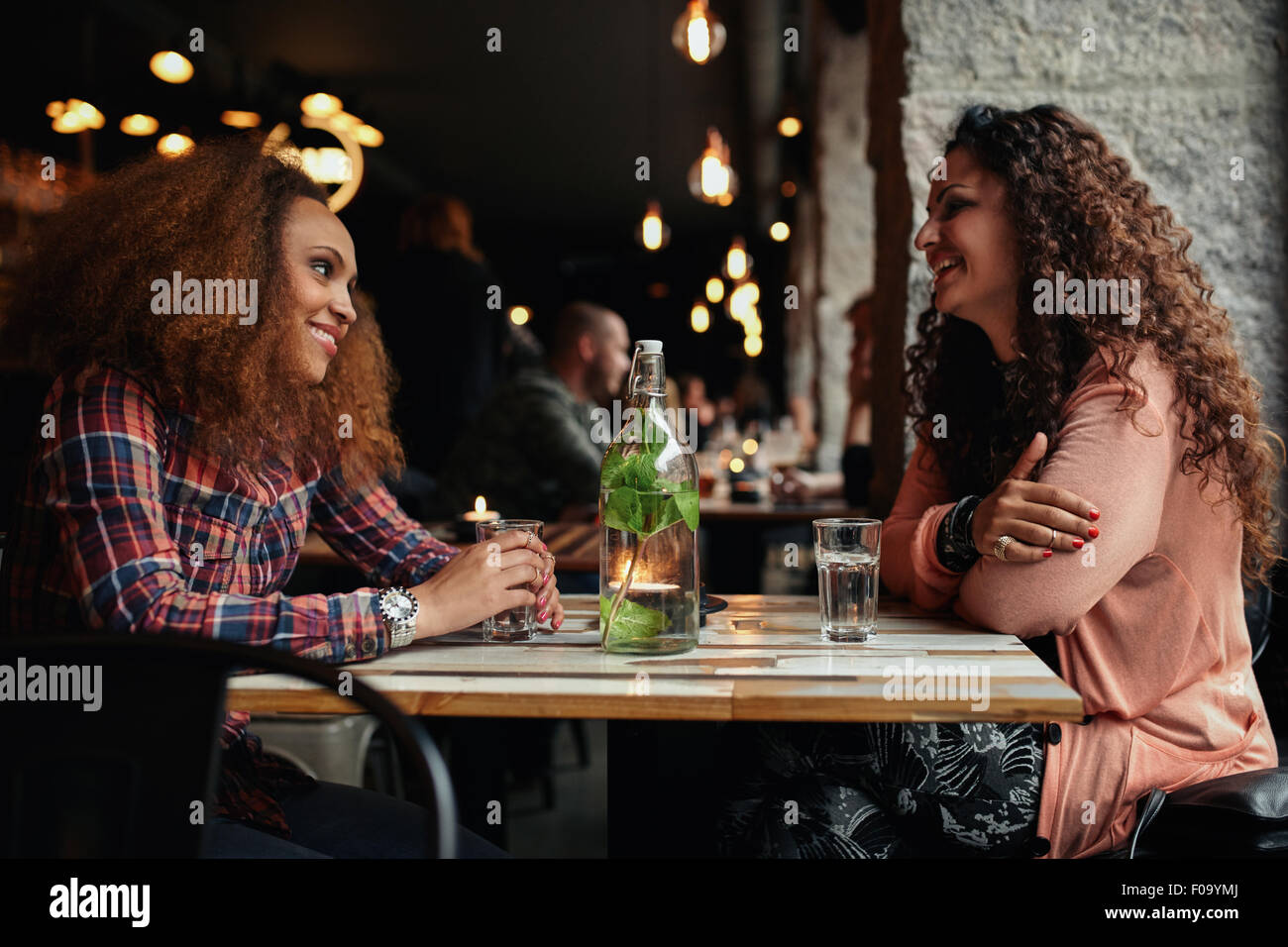 Imagen de mujeres reunión de amigos en un café. Dos mujeres jóvenes en un restaurante hablando y sonriendo. Foto de stock
