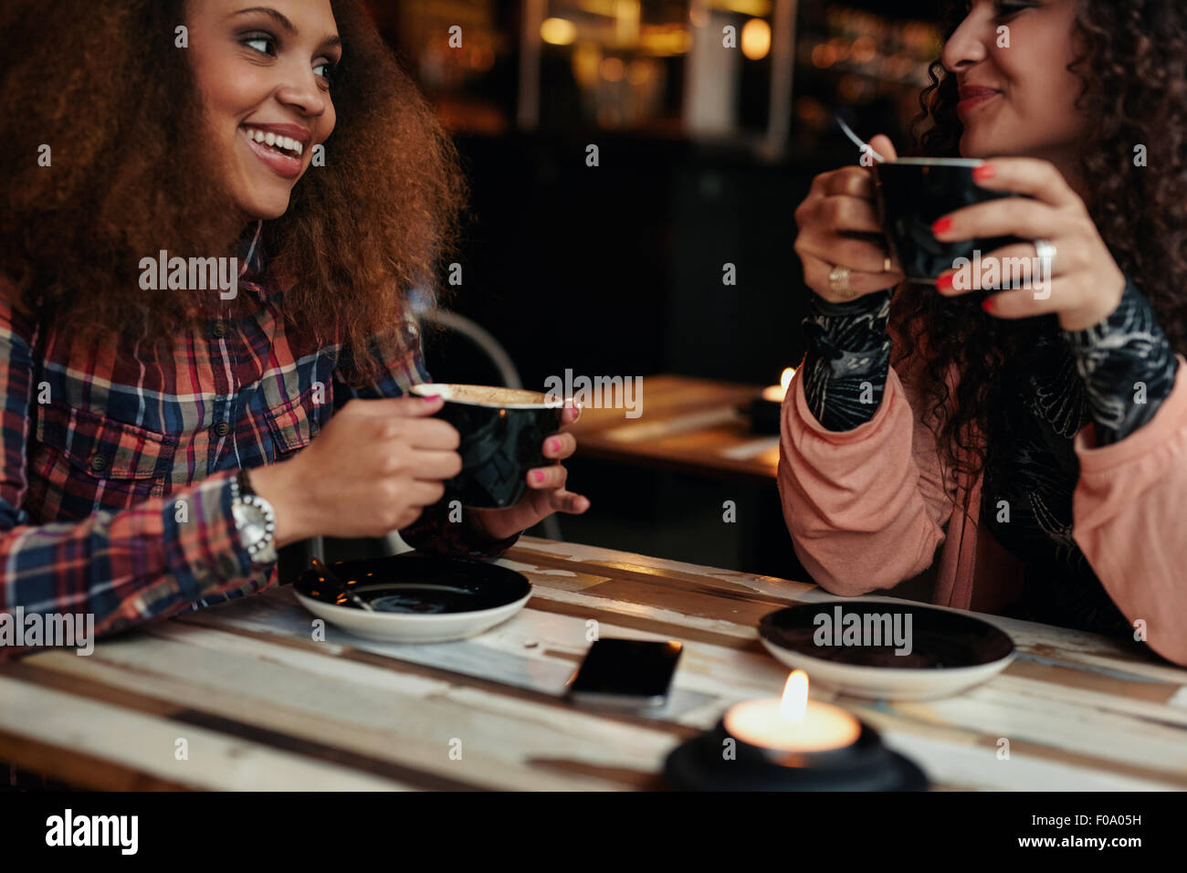 Recorta la foto de un jóvenes amigos en una cafetería. Las mujeres jóvenes en el cafe sentado en la mesa bebiendo café Foto de stock