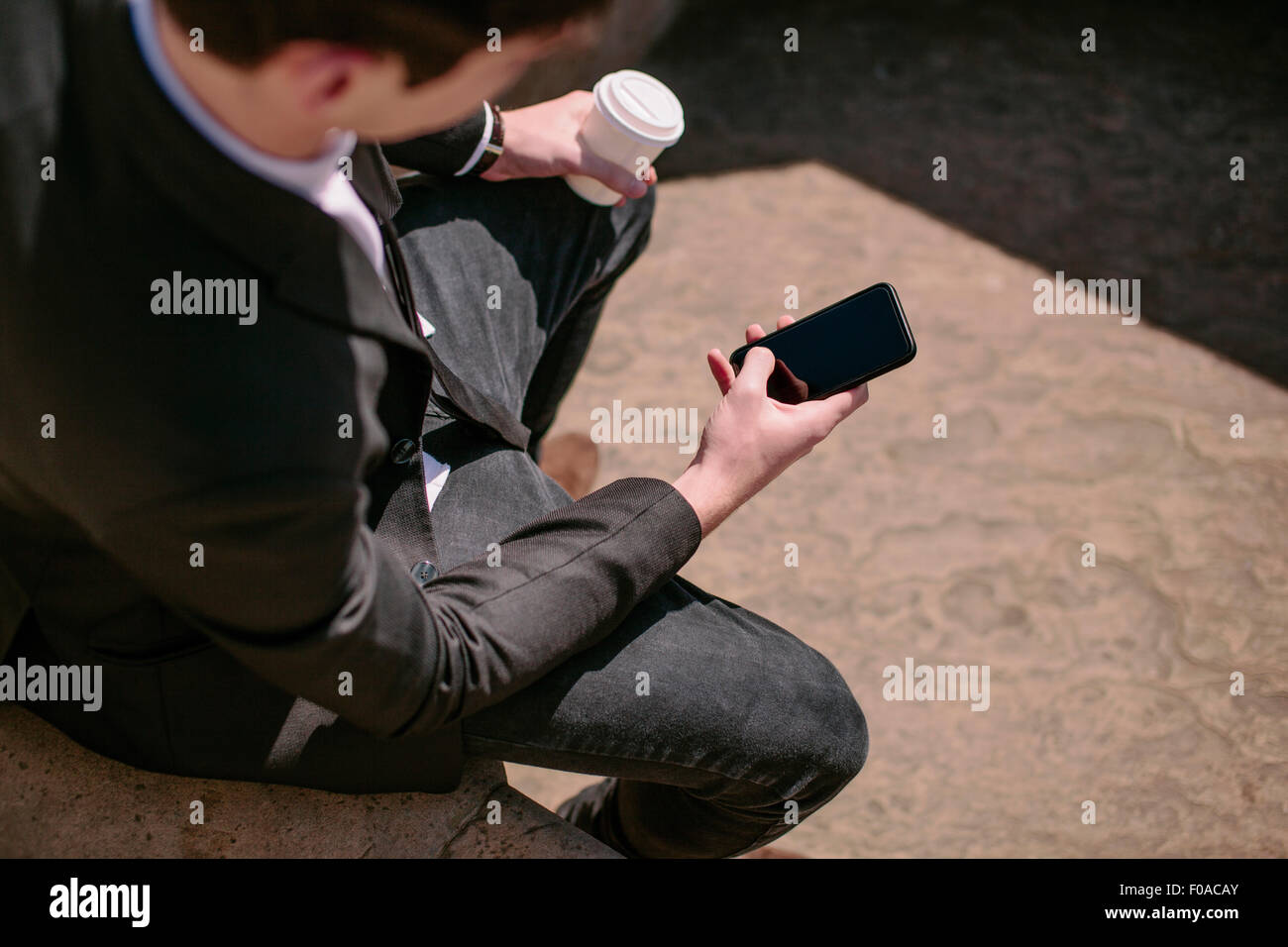 Sobre el hombro vista de joven empresario de lectura de textos del smartphone Foto de stock