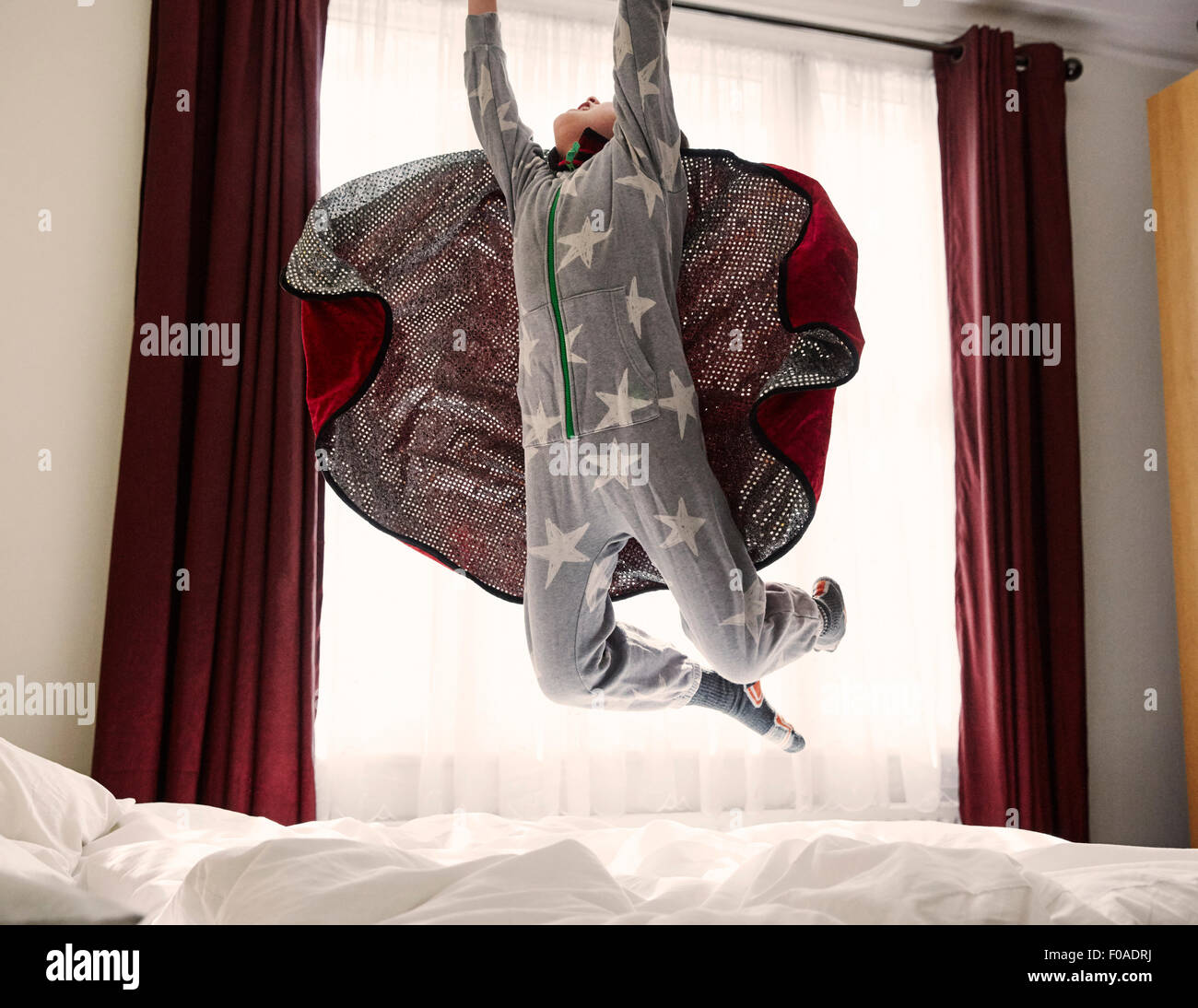 Joven llevando cabo saltar en la cama Foto de stock