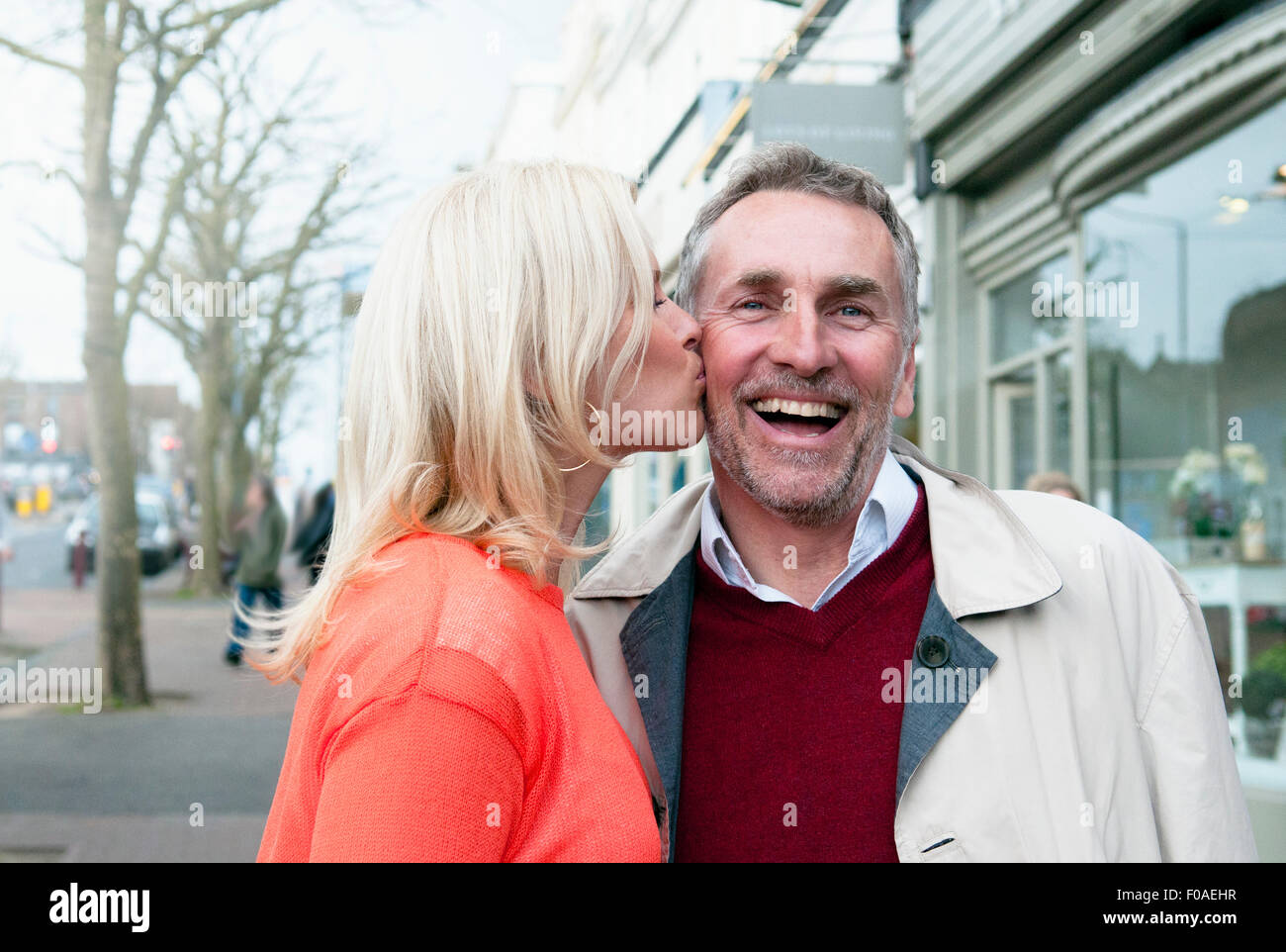 Mujer besar novio en la mejilla sobre la calle de la aldea Foto de stock