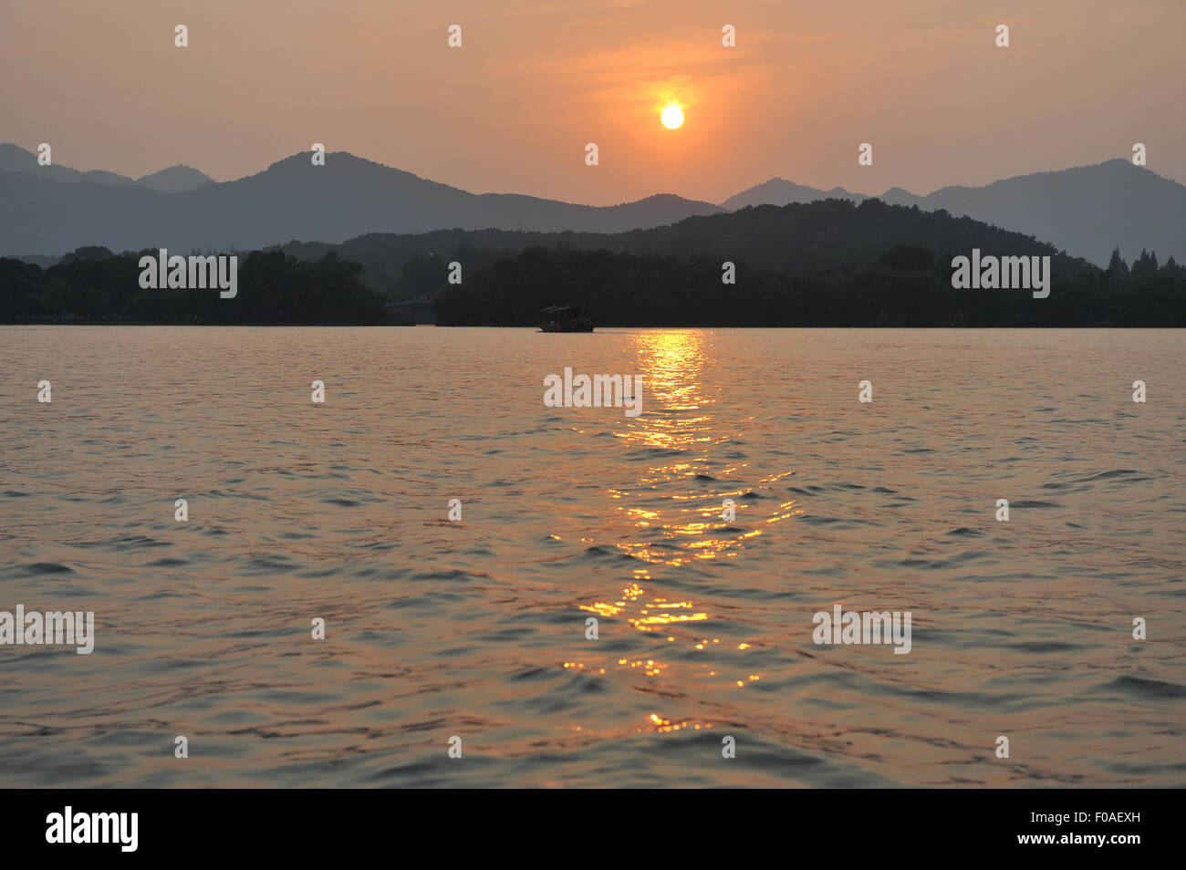 Puesta de sol sobre el lago, las montañas en la distancia, Hangzhou, China Foto de stock