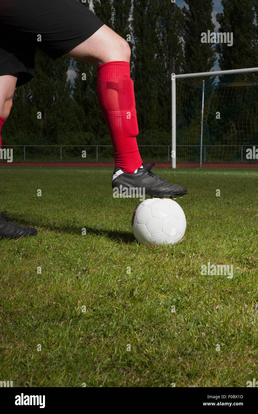 Bajo la sección de jugador de fútbol con el pie sobre el balón de la portería post Foto de stock