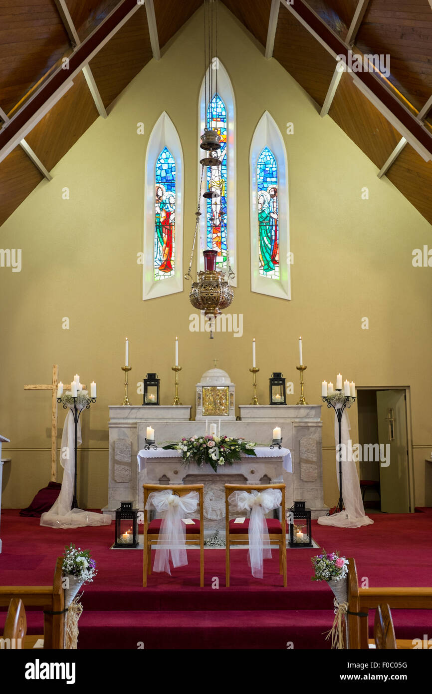 Flores de la boda con velas dispuestas sobre el altar en la iglesia católica. Foto de stock