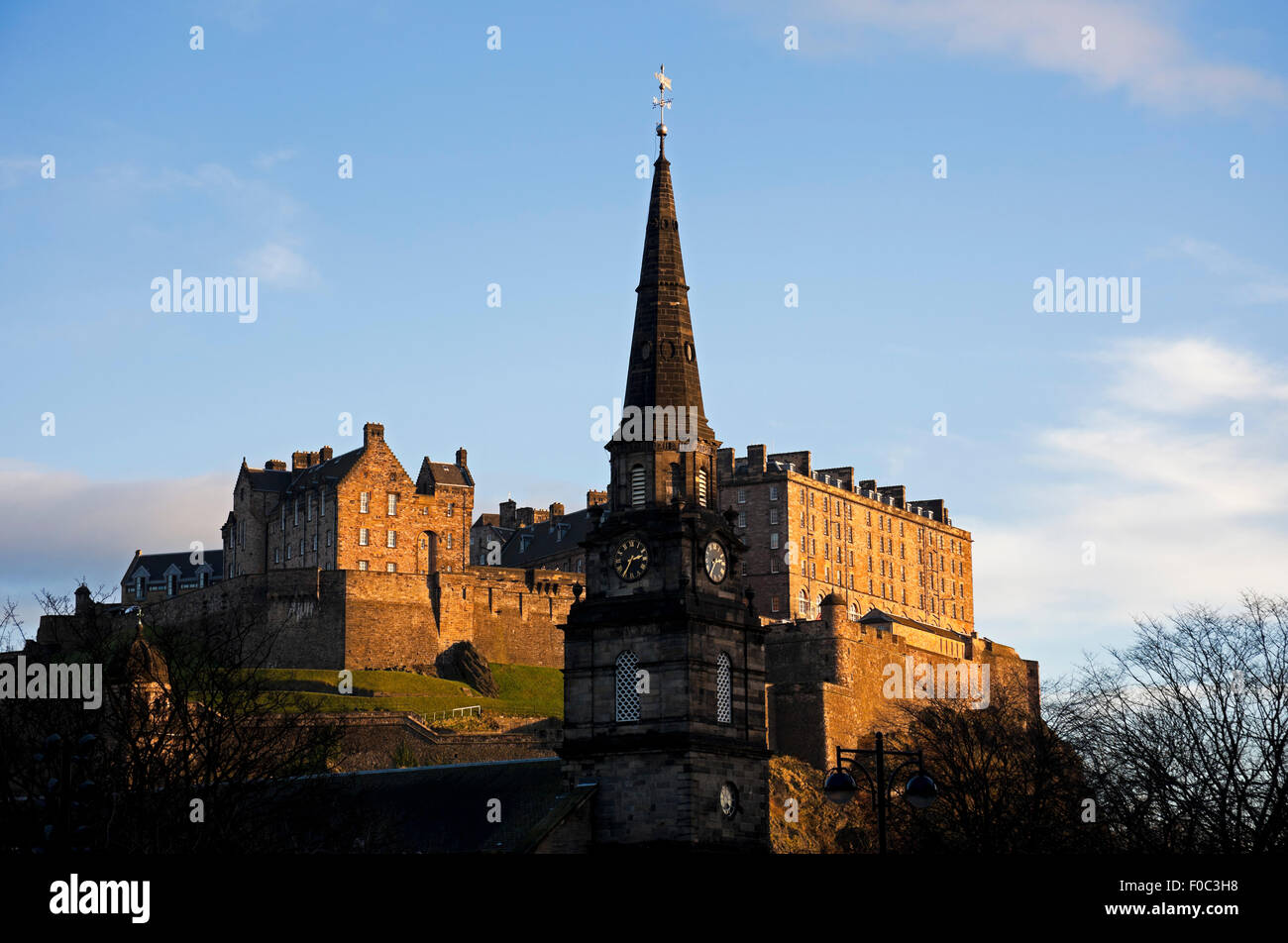 Campanario de la iglesia de St Cuthbert en primer plano con el castillo de Edimburgo en el fondo en diciembre, Escocia, Reino Unido, Europa Foto de stock