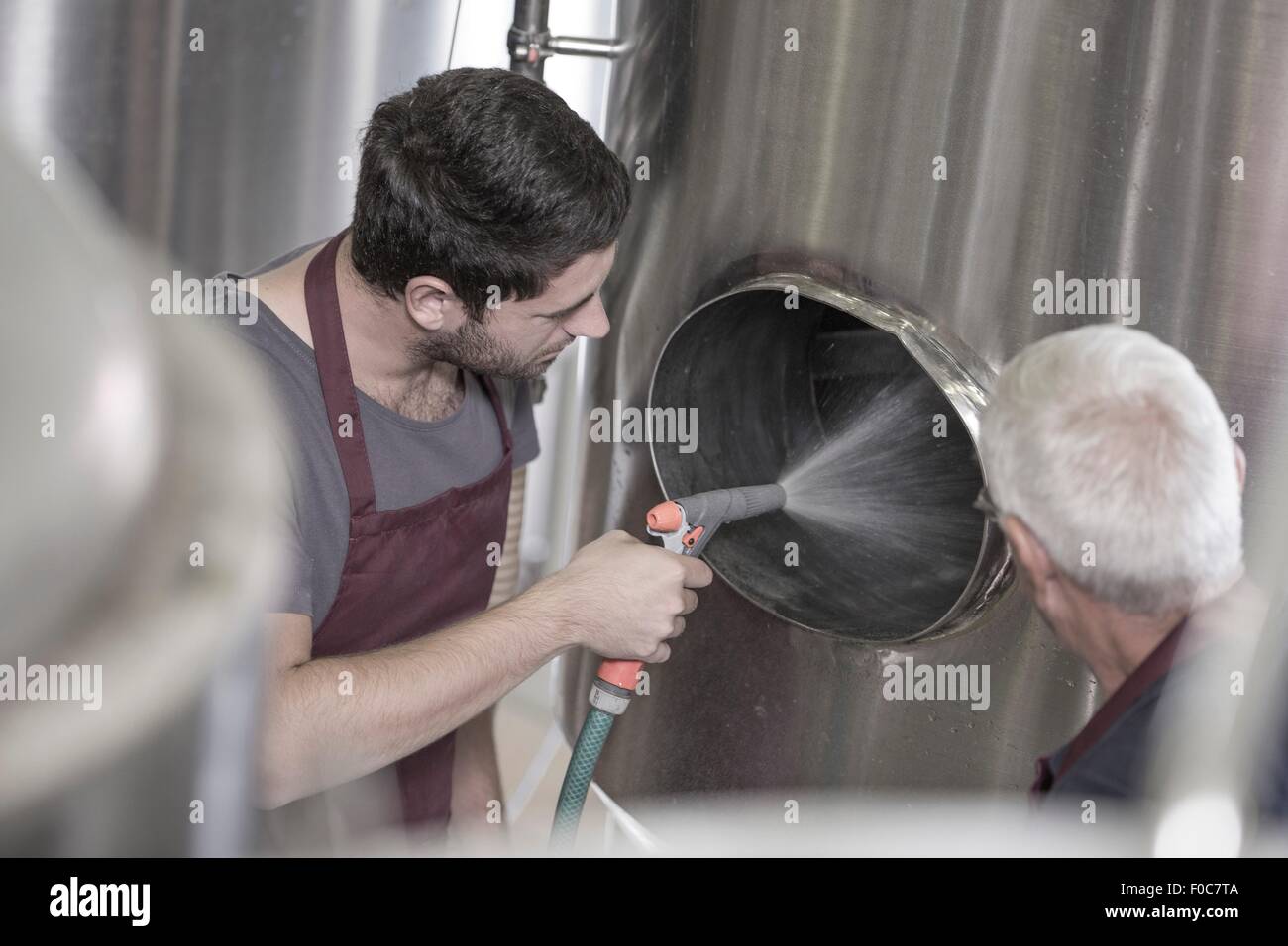 Brewer limpieza de un depósito de acero inoxidable en la cervecería Foto de stock