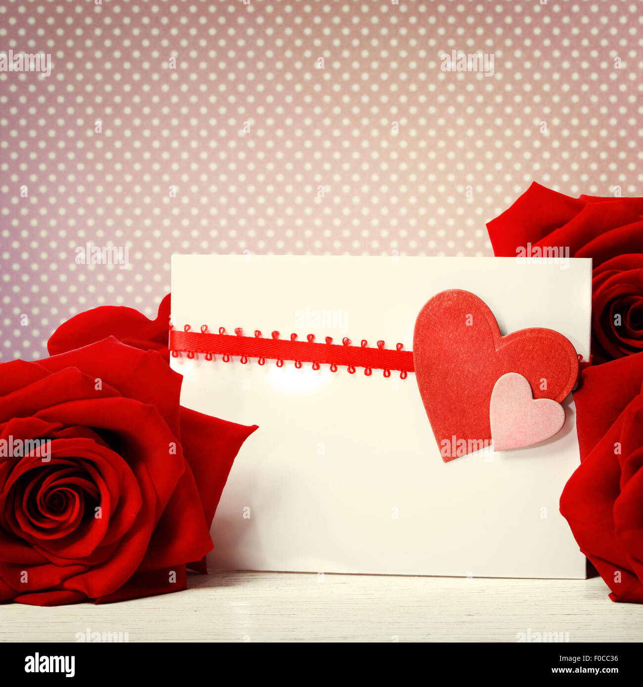 Tarjeta de felicitación de corazones con hermosas rosas rojas sobre puntos polka rosa antecedentes Foto de stock