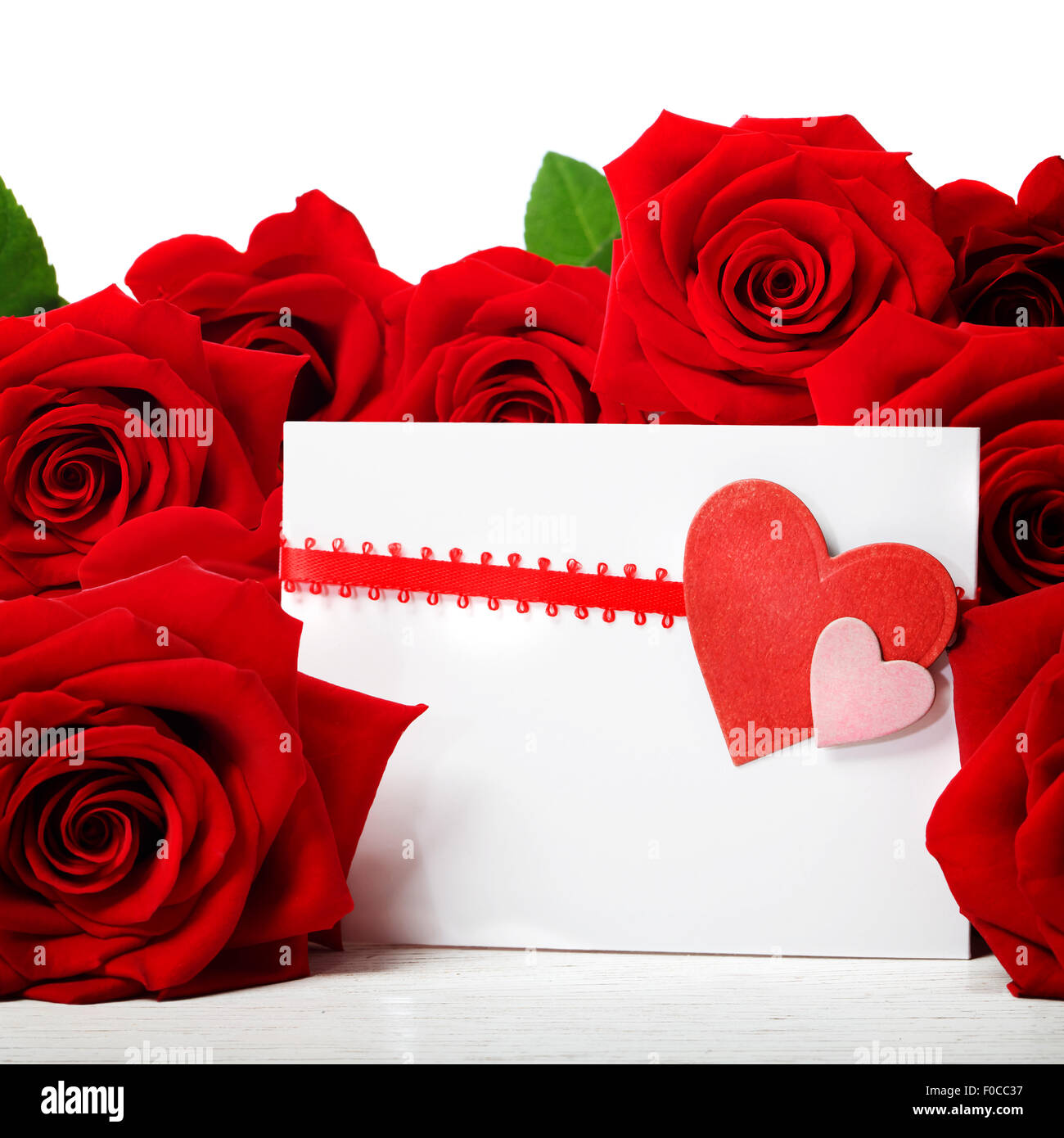 Tarjeta de felicitación de corazones con hermosas rosas rojas sobre fondo blanco. Foto de stock