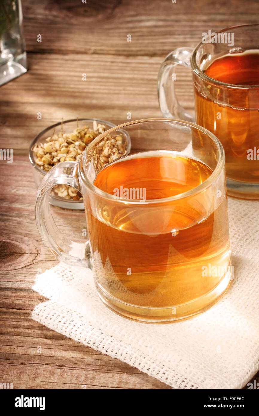 Un té de manzanilla con flores de manzanilla secas sobre mesa de madera