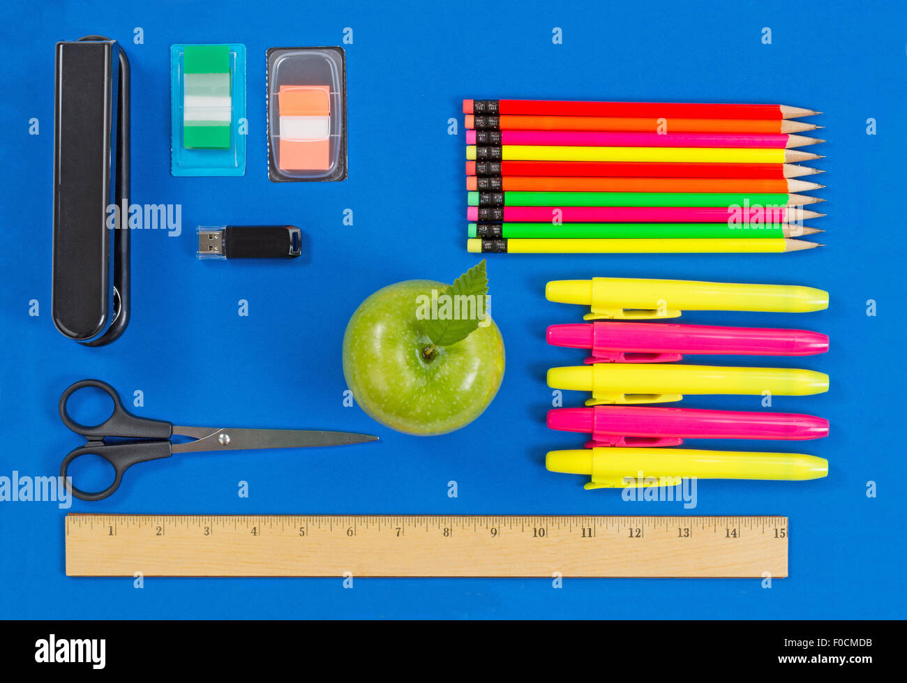 Oficina o back to school suministros consistentes en una manzana verde, resaltar los marcadores, grapadora, thumb drive, regla, tijeras, ficha de mar Foto de stock