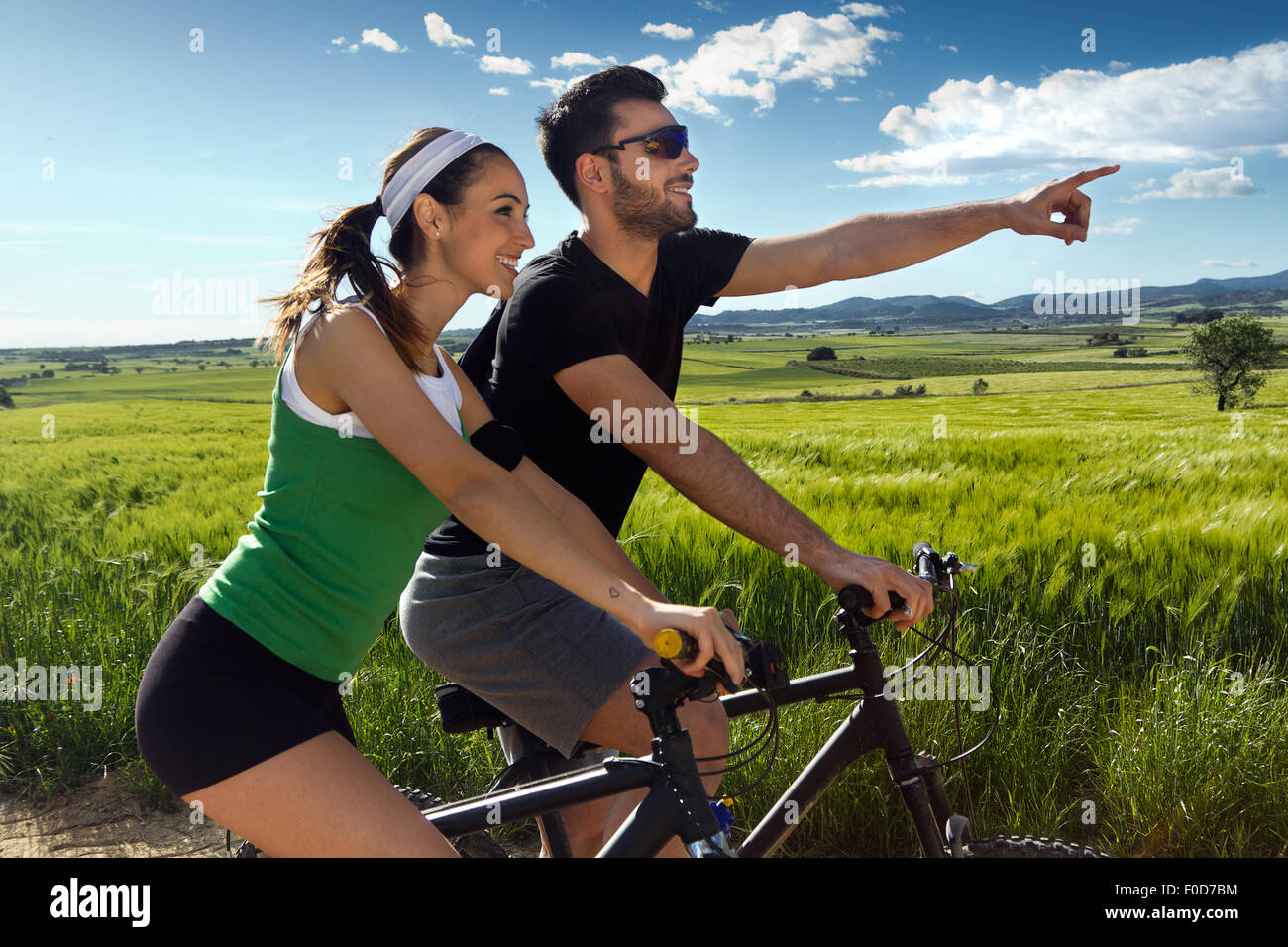 Primavera retrato de joven pareja feliz en un paseo en bicicleta en el campo Foto de stock