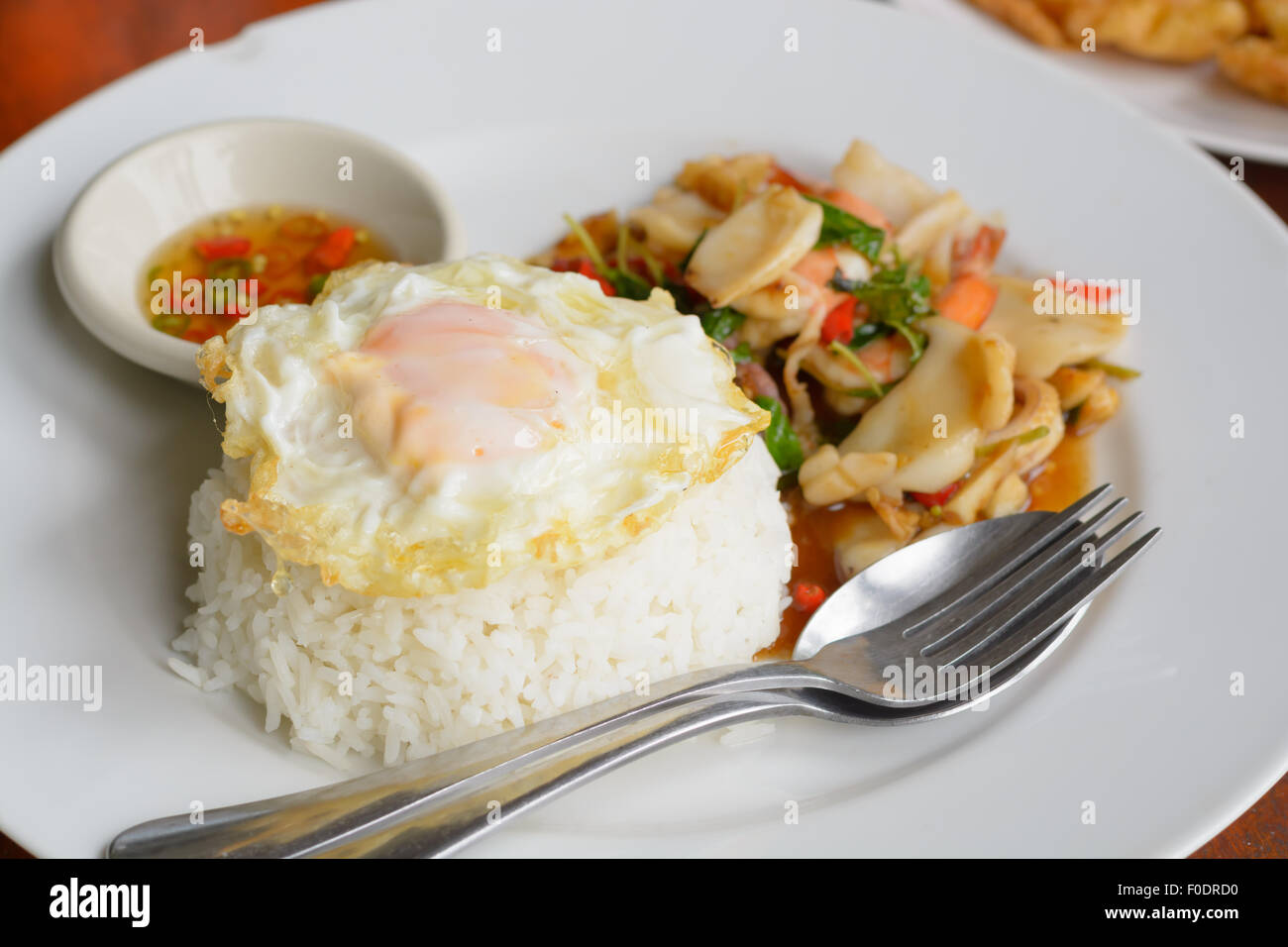 Hojas de albahaca frito arroz cocido con una mezcla de mariscos y rematado con huevo frito Foto de stock