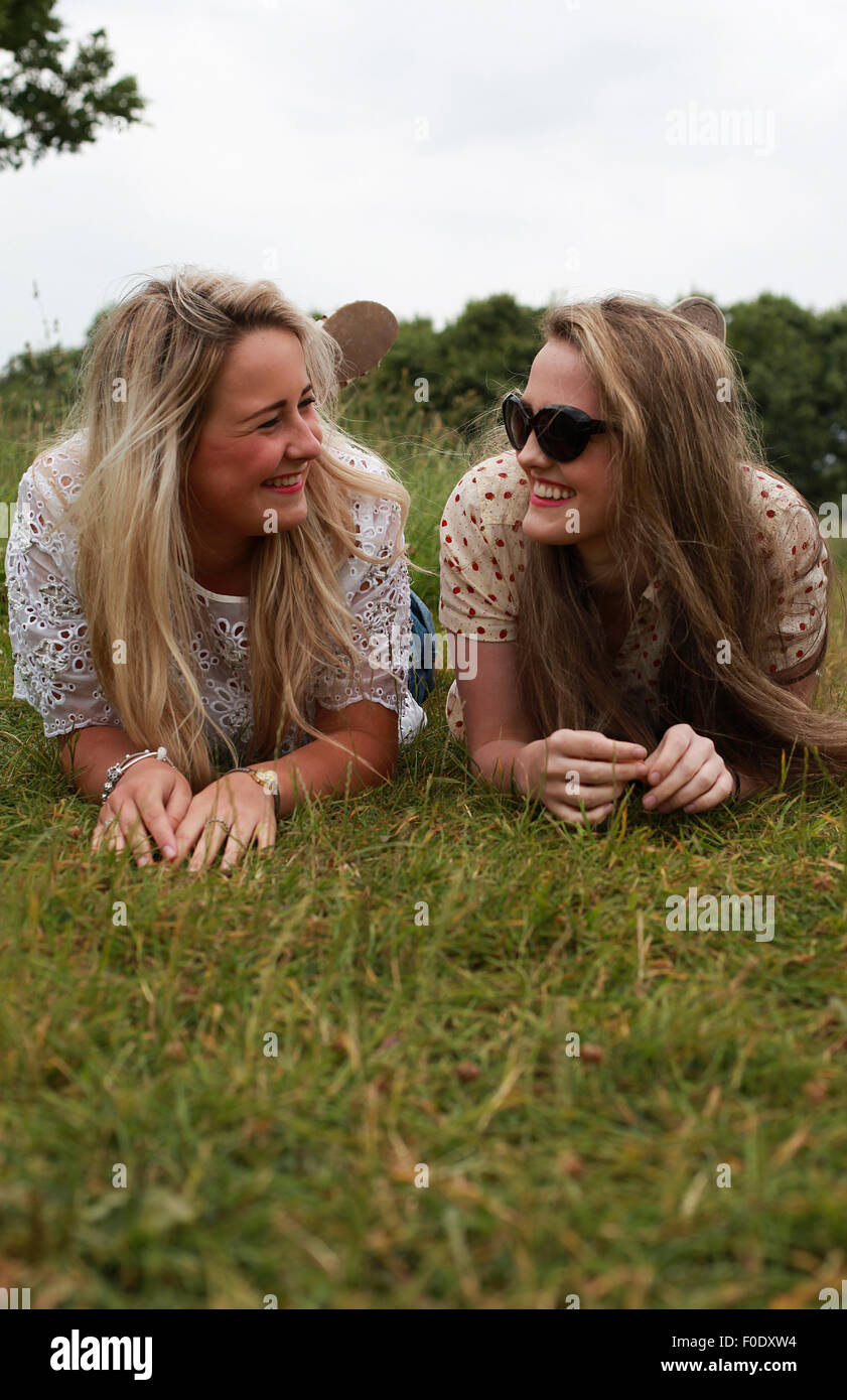 Dos chicas adolescentes tumbados en la hierba riendo Foto de stock