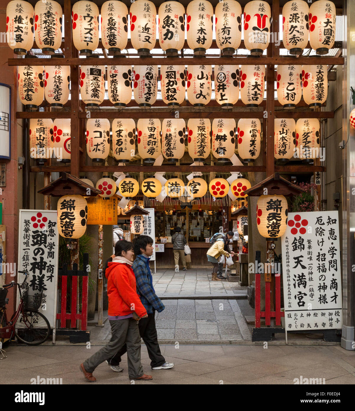 Los peatones en la entrada y dentro del templo en el mercado de Nishiki en Kyoto, Japón. Linternas japonesas colgando en la parte delantera. Foto de stock