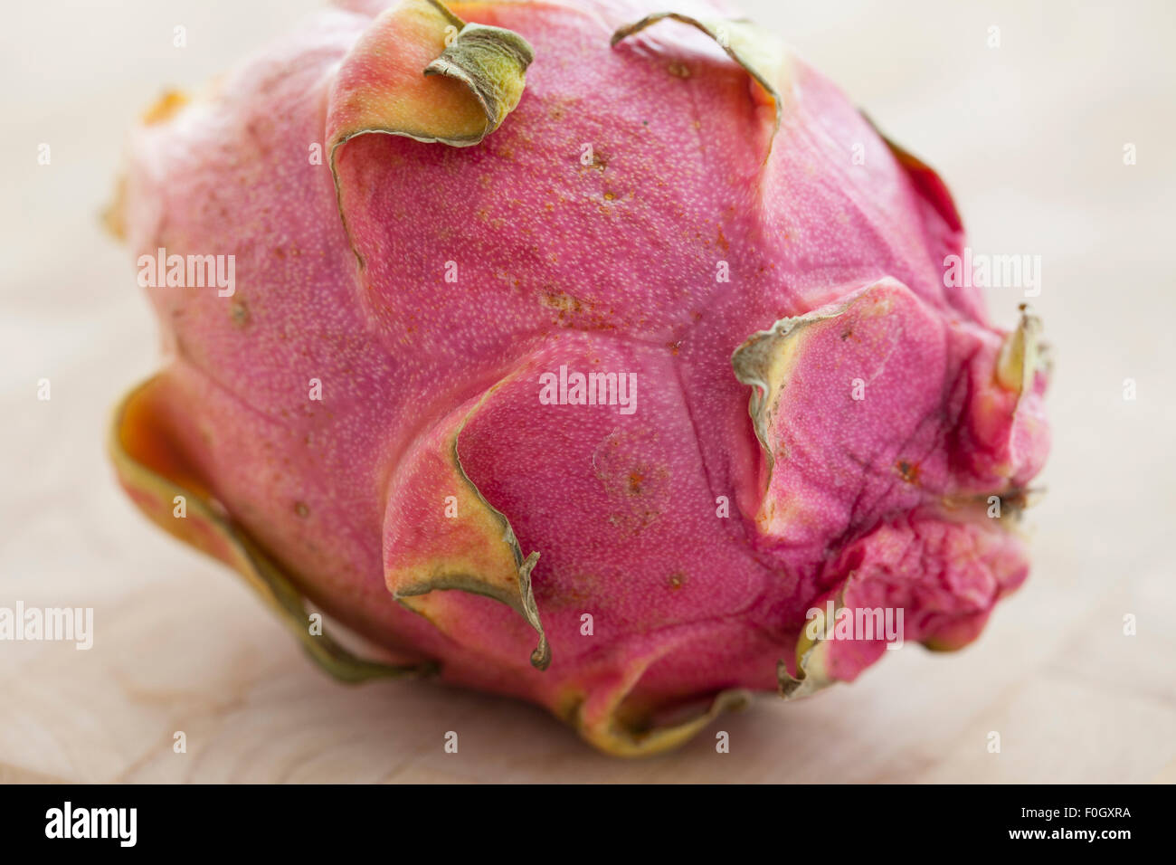Un dragón pitaya o fruta sobre una superficie de madera fotografiado con la luz de la ventana. Foto de stock