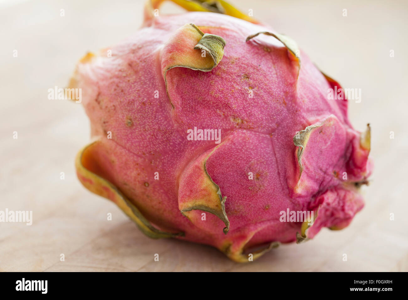 Un dragón pitaya o fruta sobre una superficie de madera fotografiado con la luz de la ventana. Foto de stock