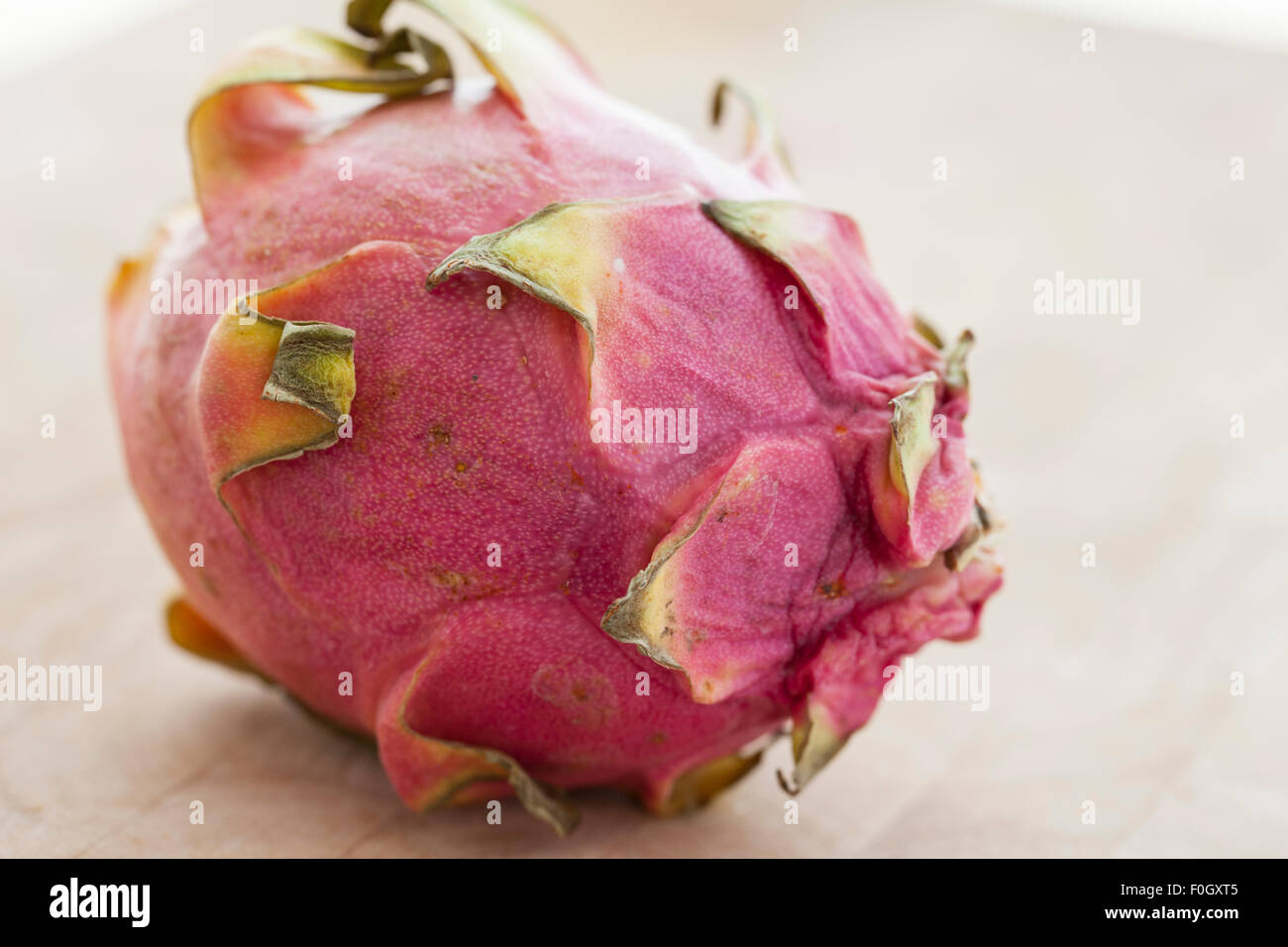Un dragón pitaya o fruta sobre una superficie de madera fotografiado con la luz de la ventana. Foto de stock
