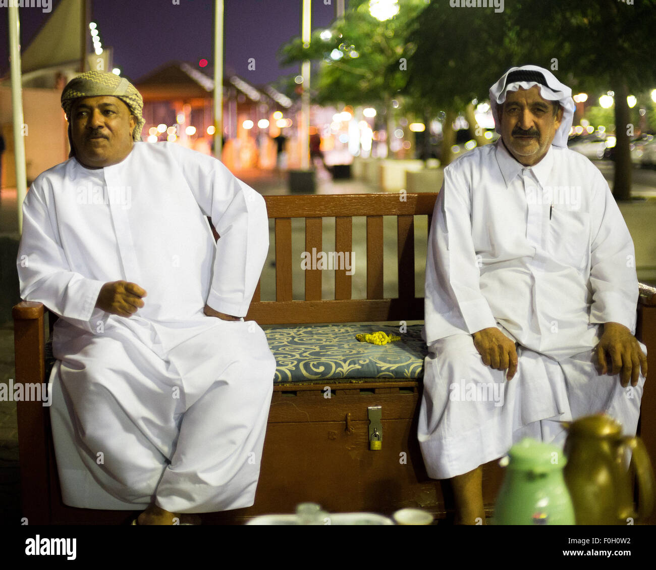 Dos de los Emiratos los hombres beben té junto a la cala de Dubai, EAU. Foto de stock